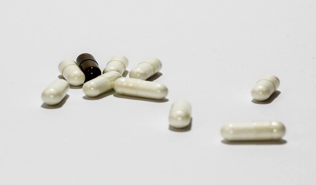 Close-up of white and black  pills scattered on a surface