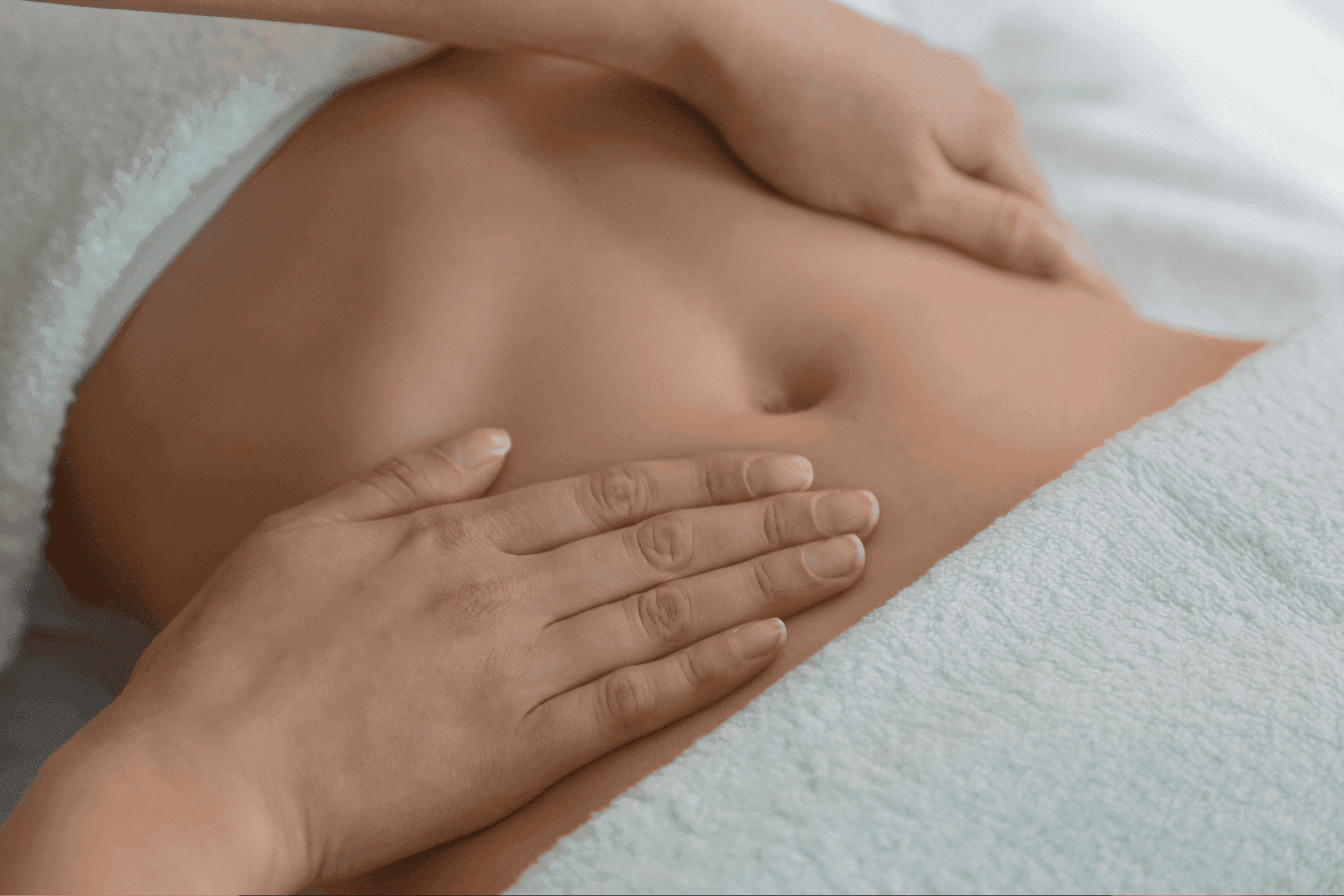 A close-up of a person’s abdomen while receiving a gentle abdominal massage.