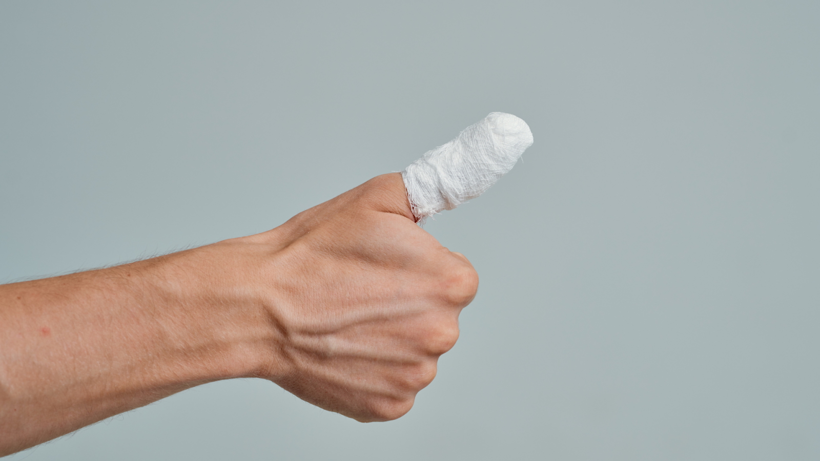 A hand with a bandaged thumb, indicating an injury