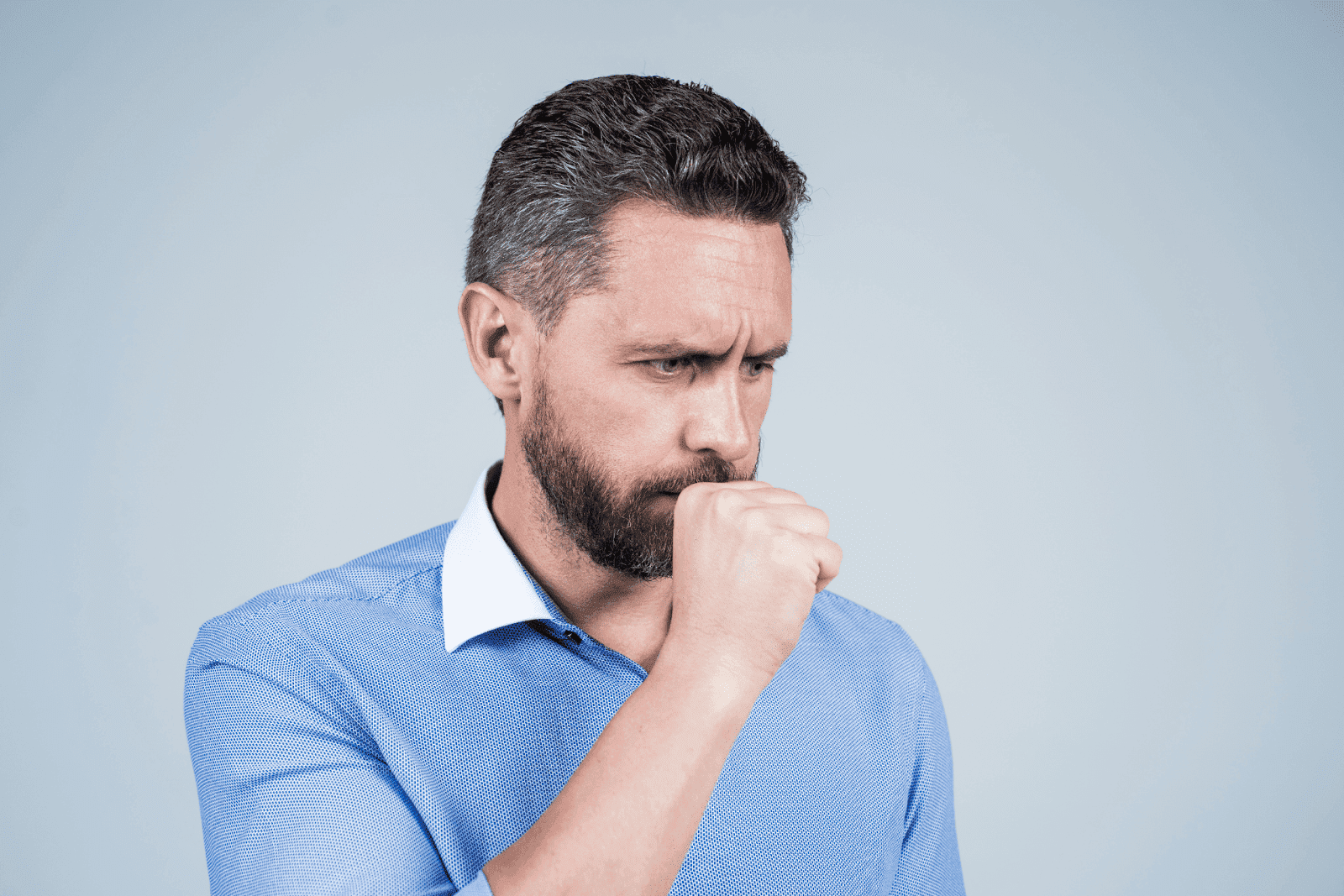A man coughing into his hand while looking unwell.