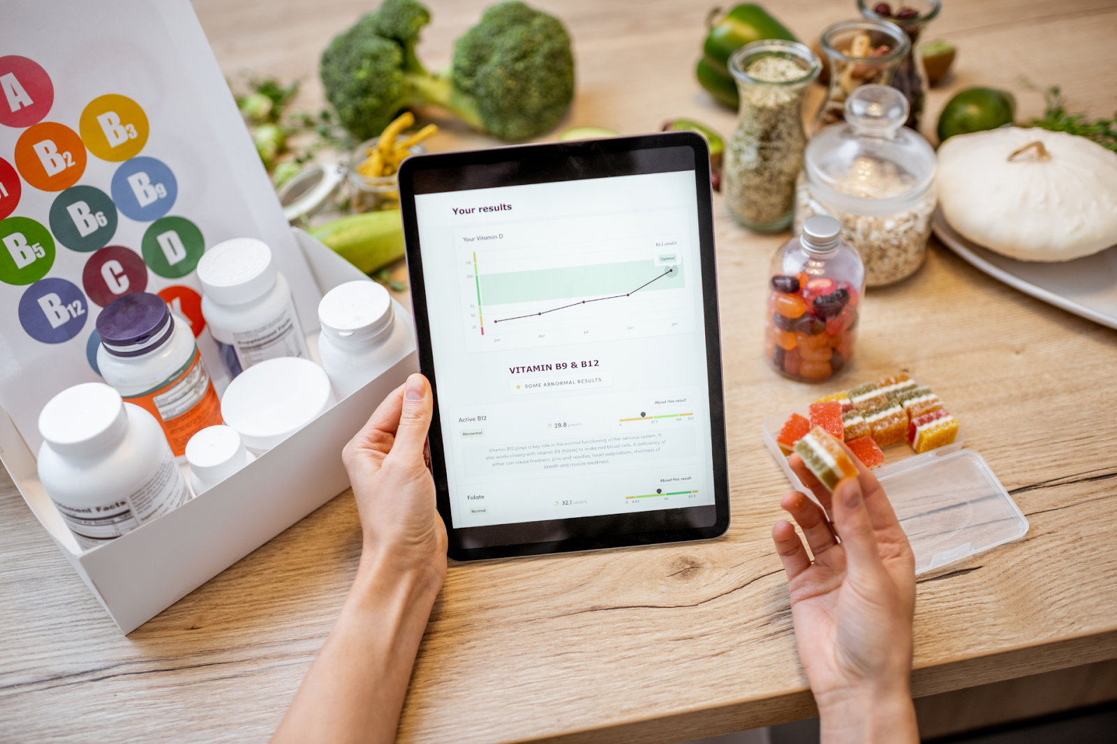 A tablet displaying vitamin test results on a table with supplements and fresh food.