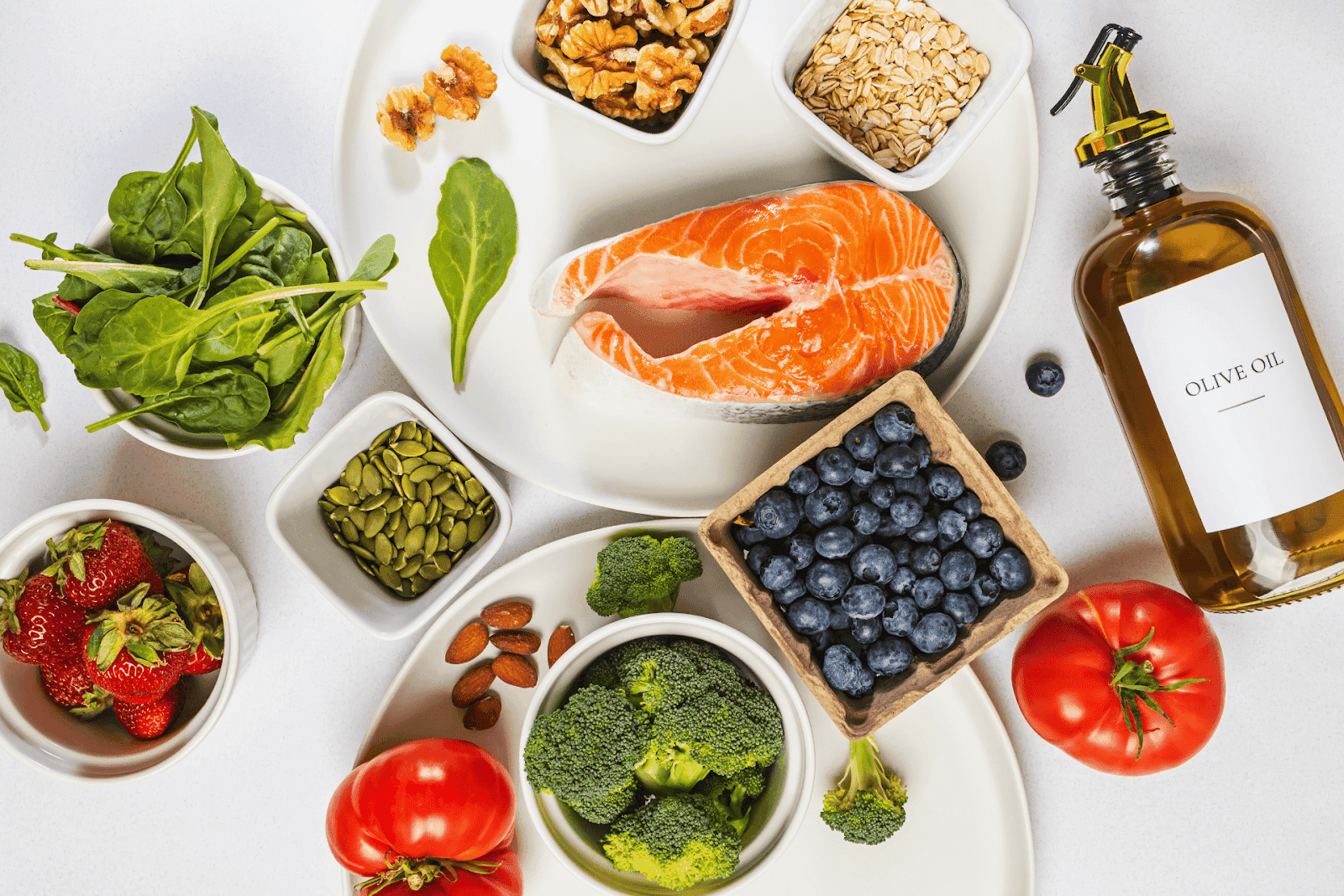 Assortment of healthy foods including salmon, vegetables, nuts, and olive oil.