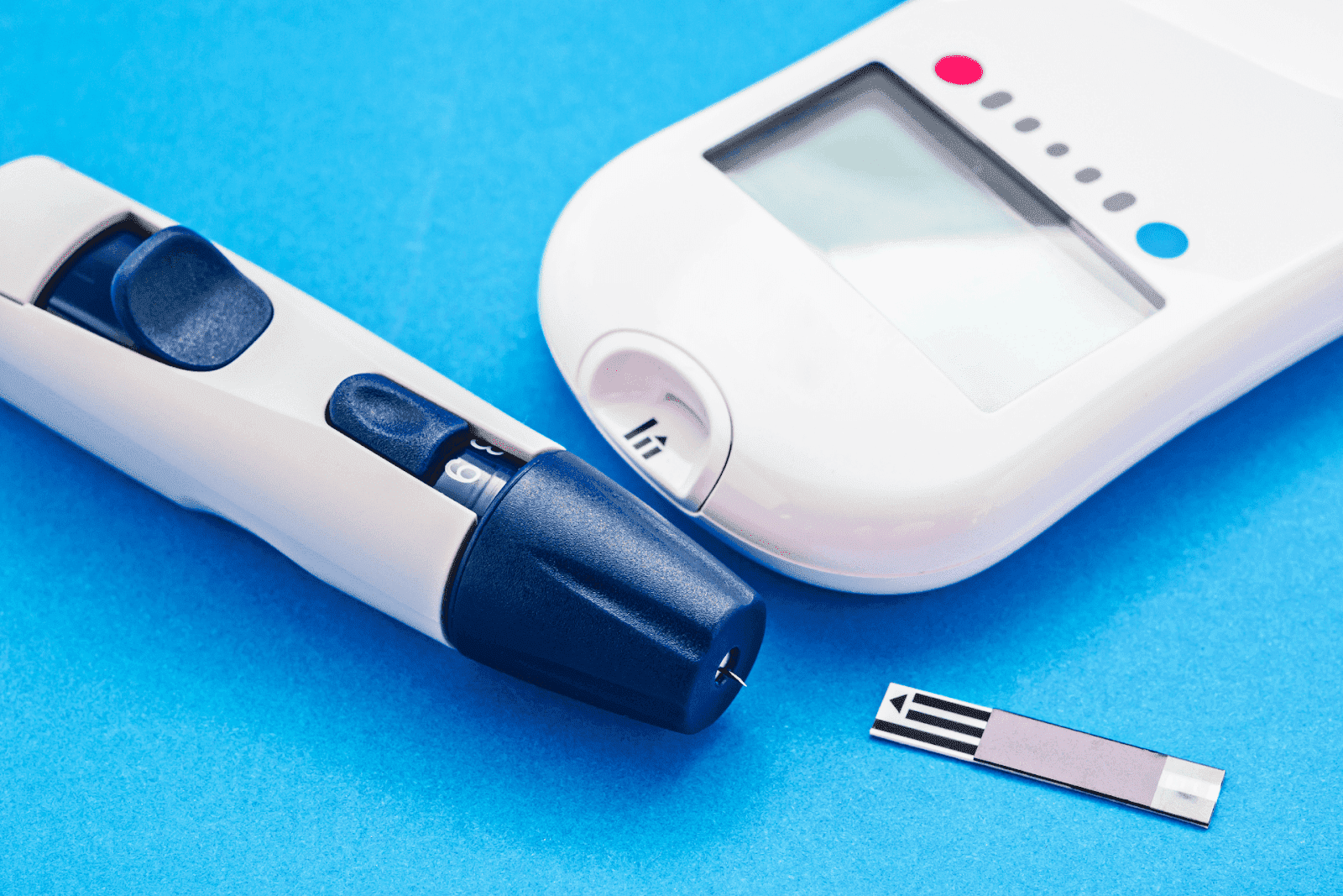 Blood glucose meter, lancet device, and test strip on a blue background