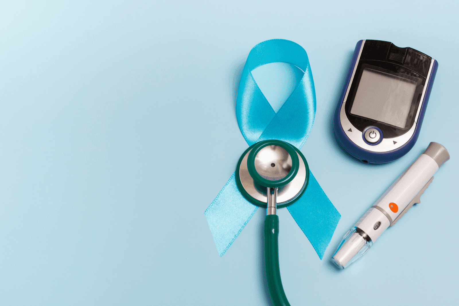 Blue awareness ribbon with a stethoscope, blood glucose meter, and lancing device on a light blue background.