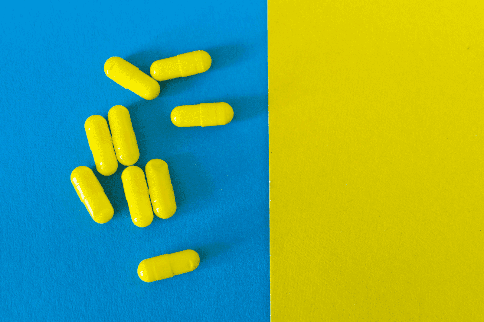 Bright yellow capsules scattered on a blue and yellow background