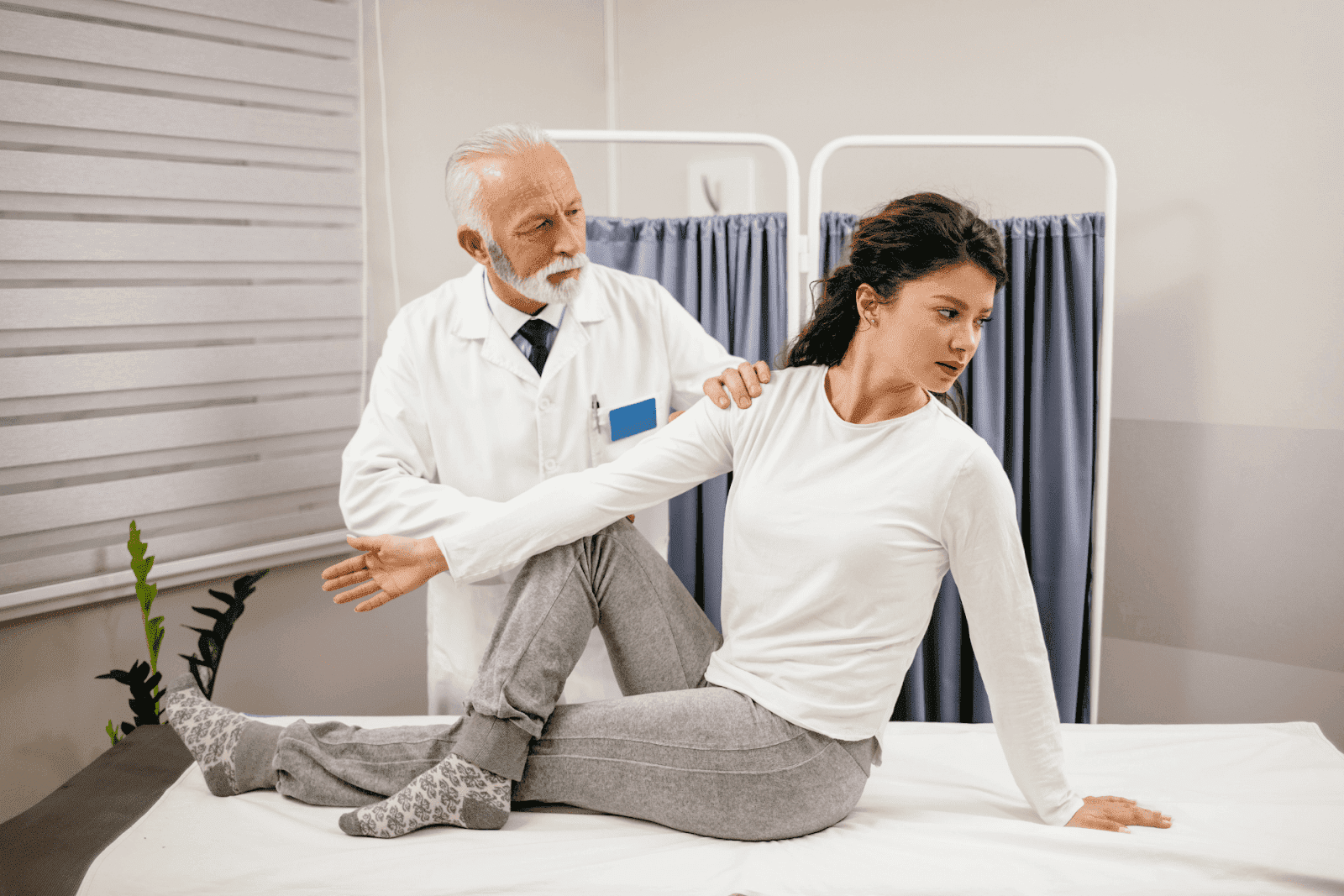 Clinician assisting a patient with a seated spinal mobility or rotation exercise during a physical examination or therapy session.