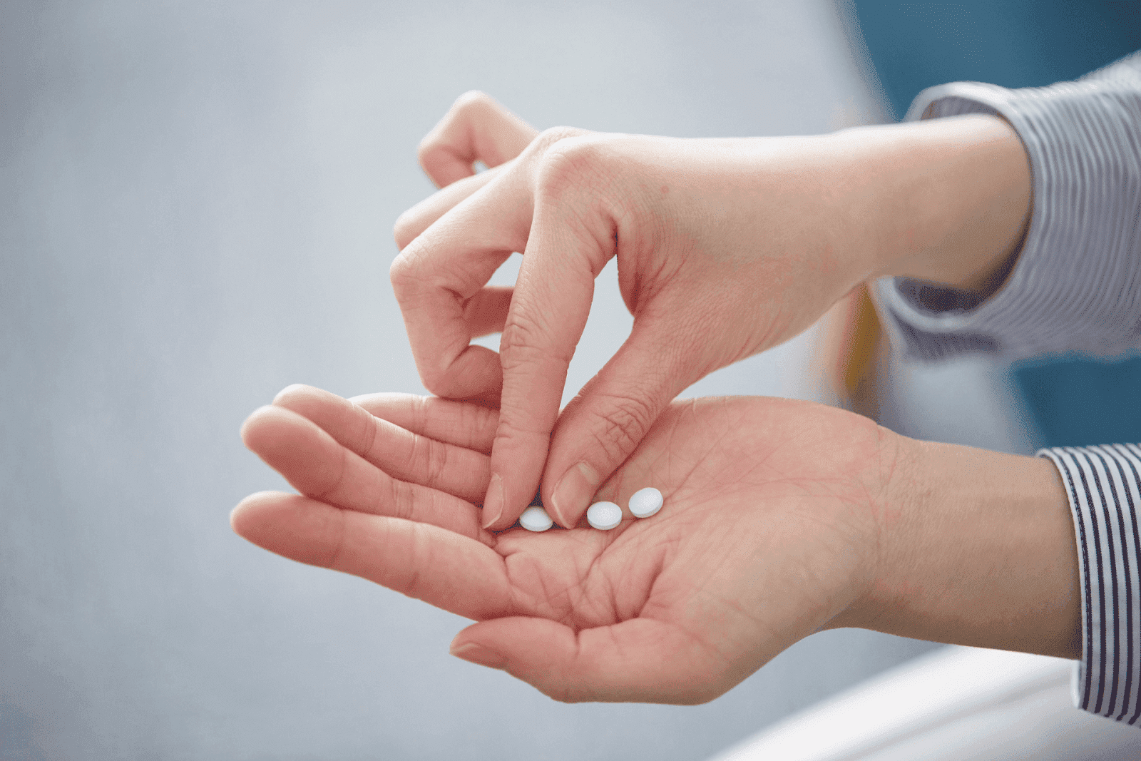 Close-up of a person holding small white pills in their hand