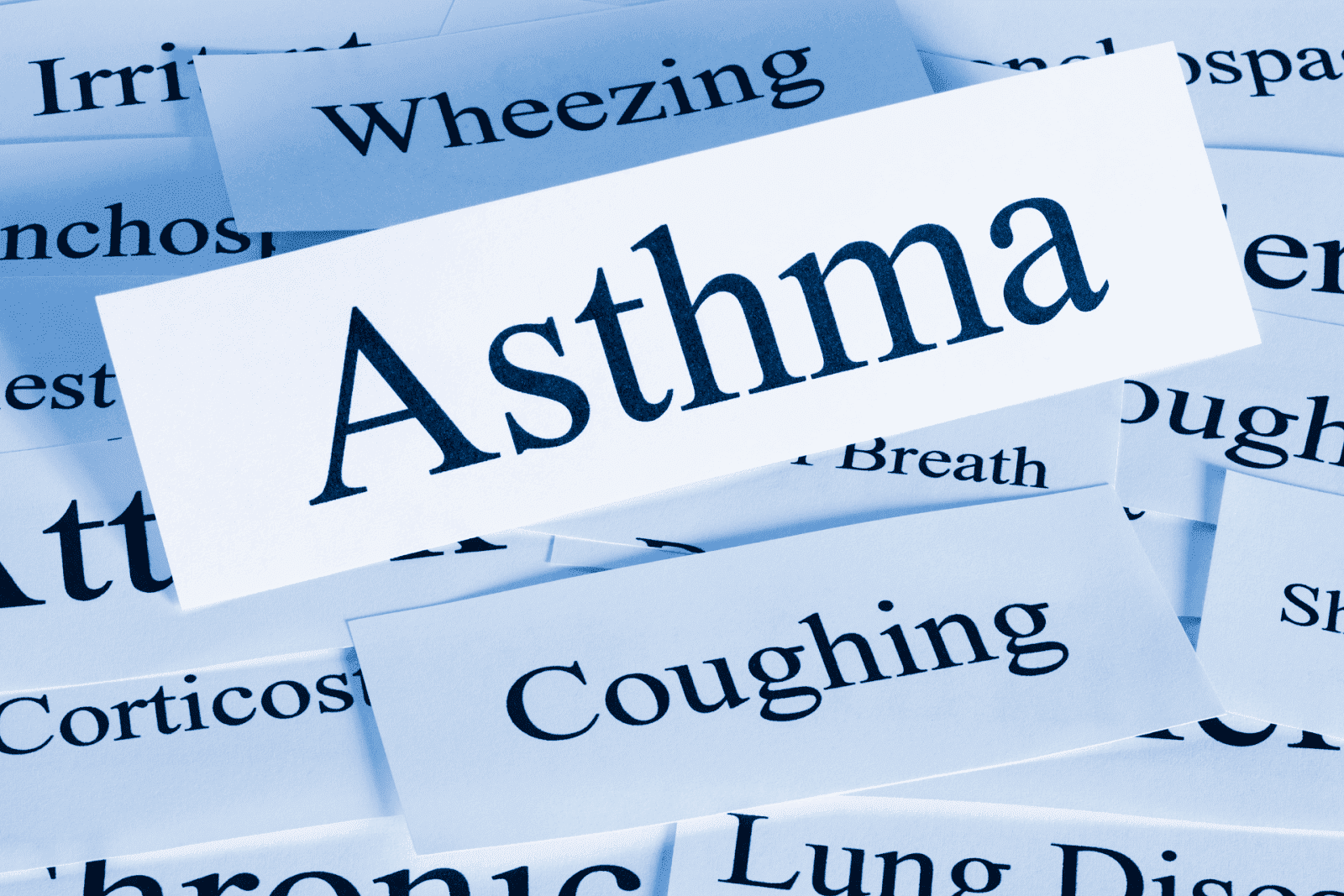 Close-up of the word “Asthma” surrounded by related symptom terms like coughing and wheezing