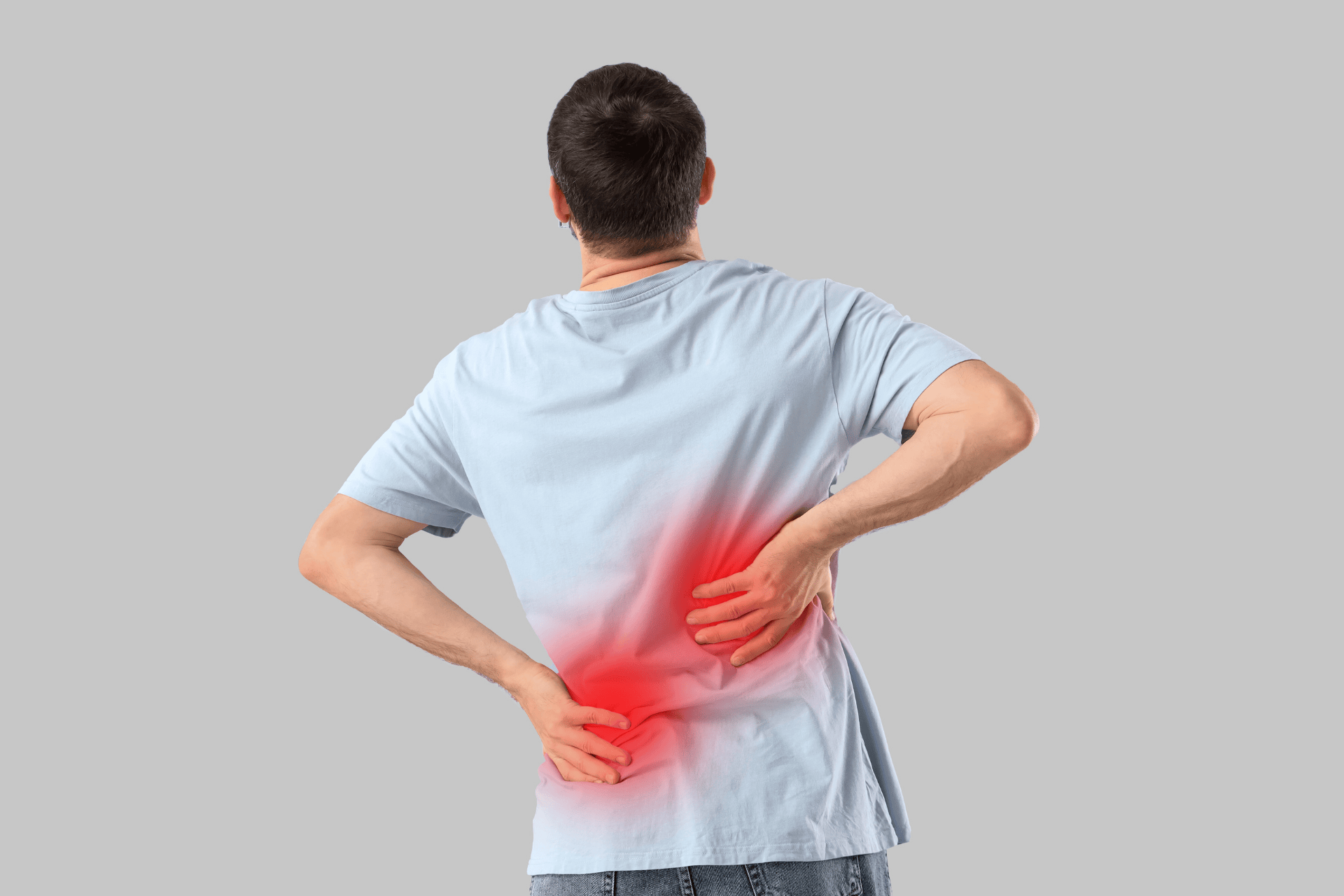 A man stands with his back to the camera, holding his lower back with both hands, with a red highlighted area indicating low back pain.