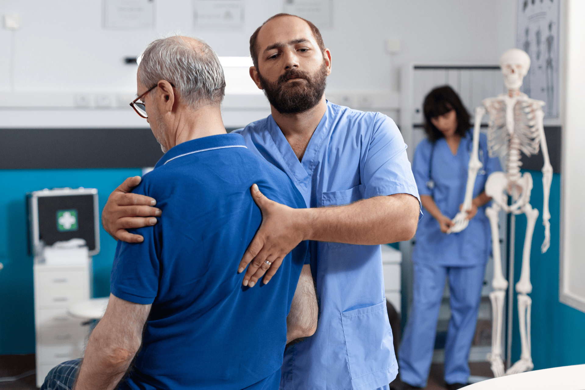 A healthcare professional assists an older man in gently stretching his back by guiding his upper body in a clinical setting.