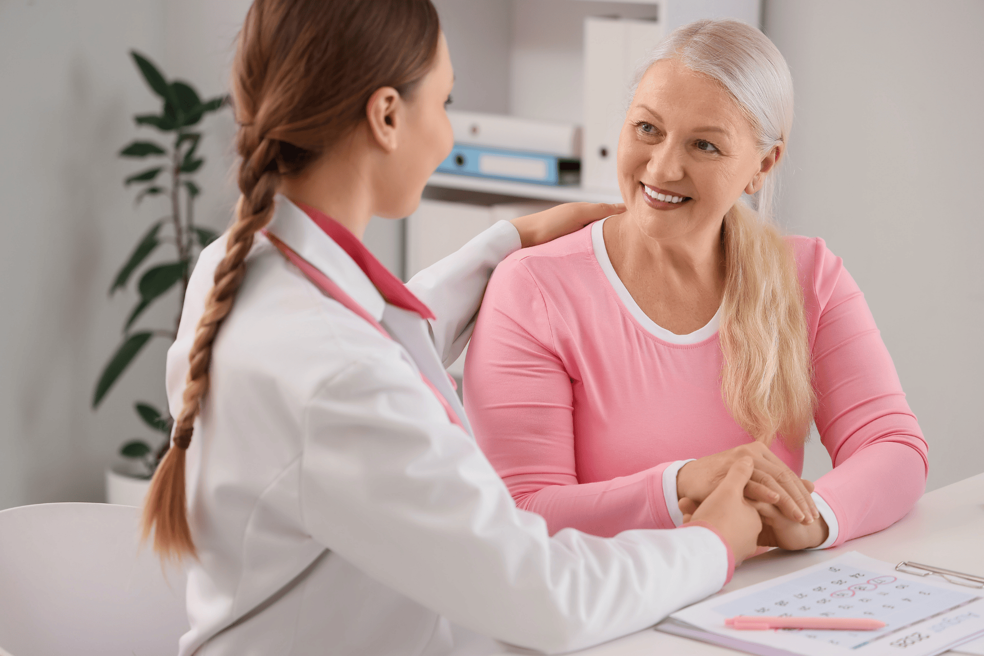Doctor reassuring a smiling older woman during a medical consultation in an office.