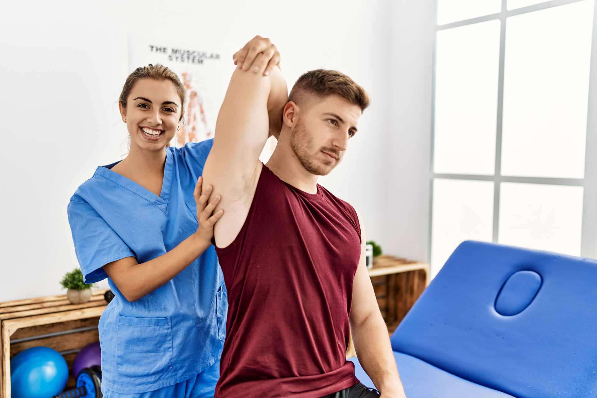 Physical therapist assisting a man with a shoulder stretch in a clinic.