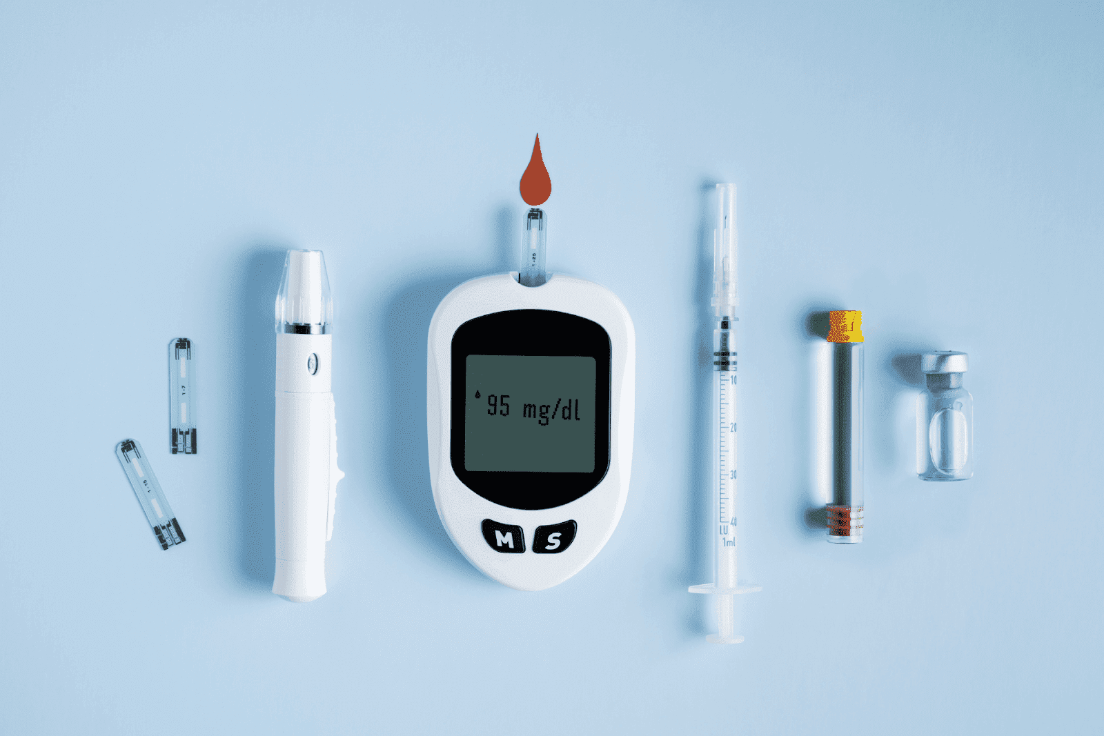 Diabetes testing supplies, including a glucose meter, syringe, and vials on a blue background.