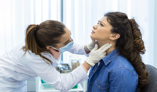 Doctor carefully examining the neck of a seated patient in a clinic.