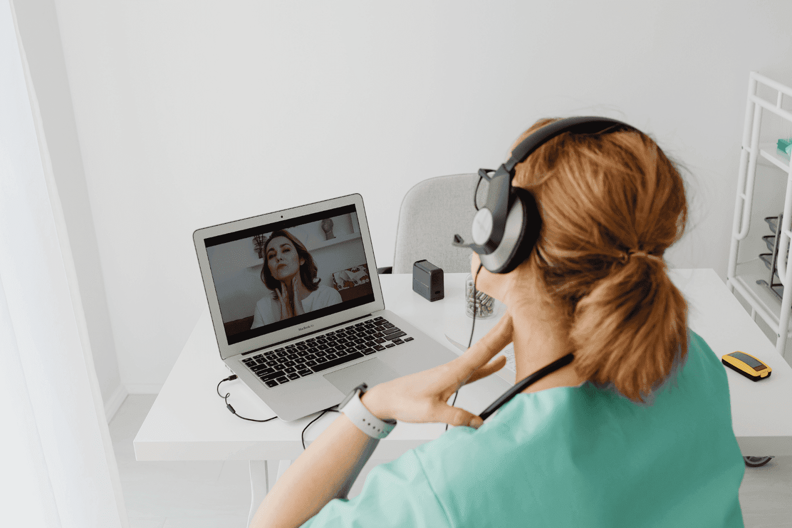 Doctor conducting an online consultation with a patient, pointing to her throat on a laptop screen