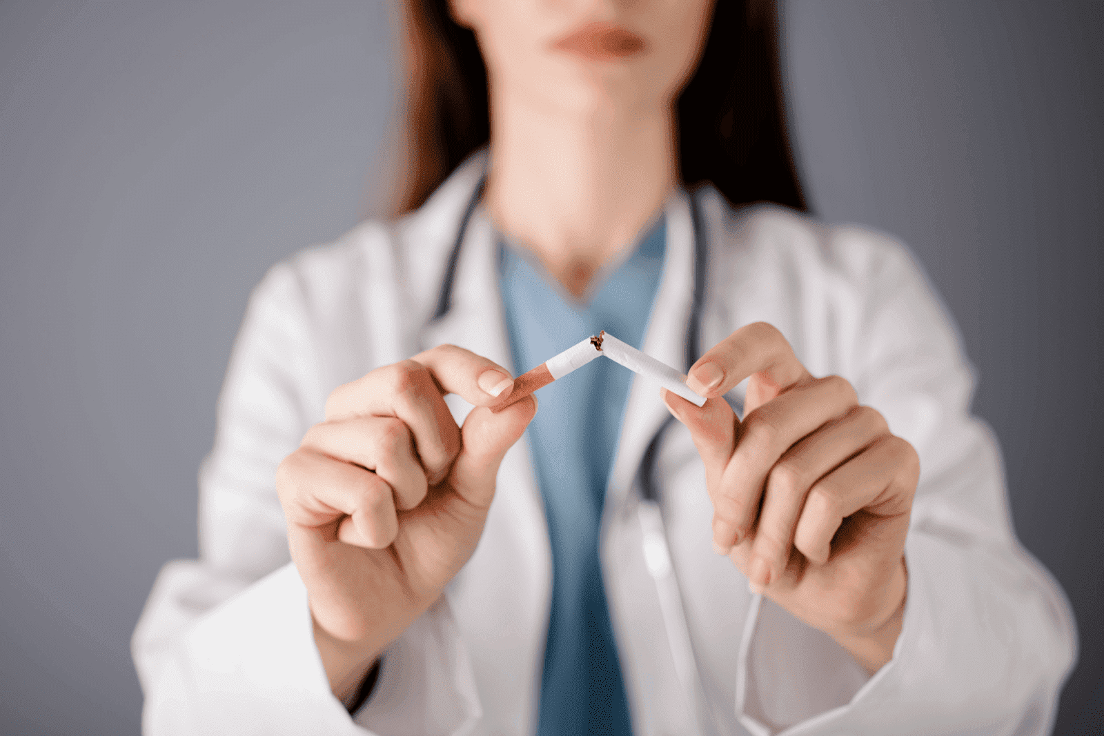 Doctor in a lab coat breaking a cigarette in half