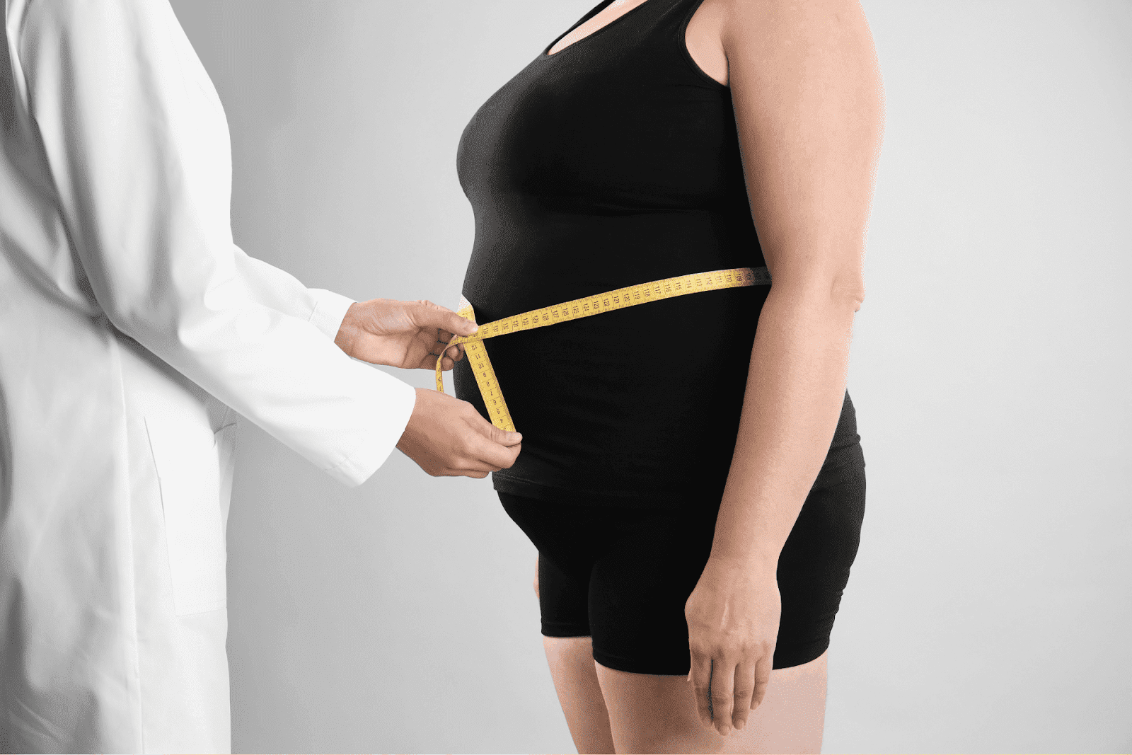 Doctor measuring a patient’s waist with a tape measure