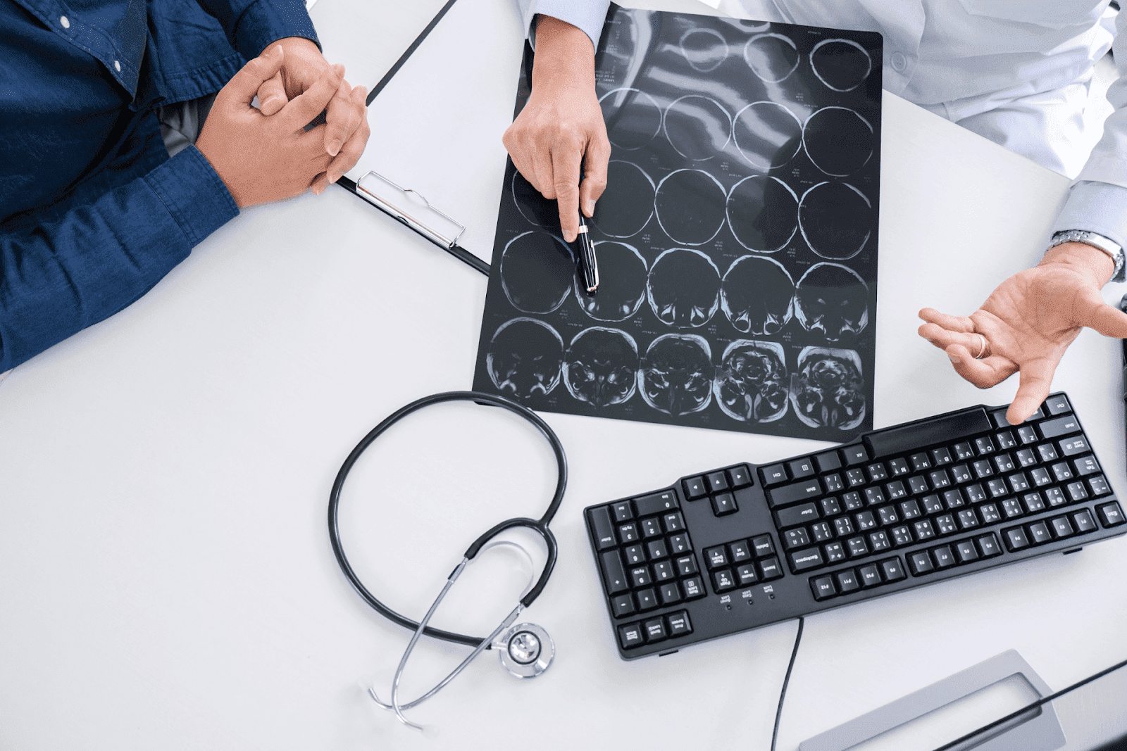 Doctor showing brain scan to patient on a desk.