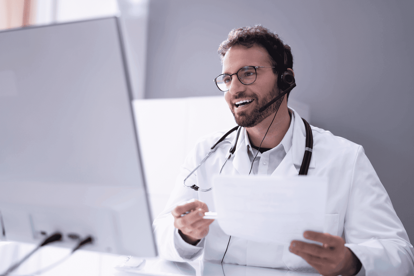 Doctor wearing a headset, smiling during an online consultation