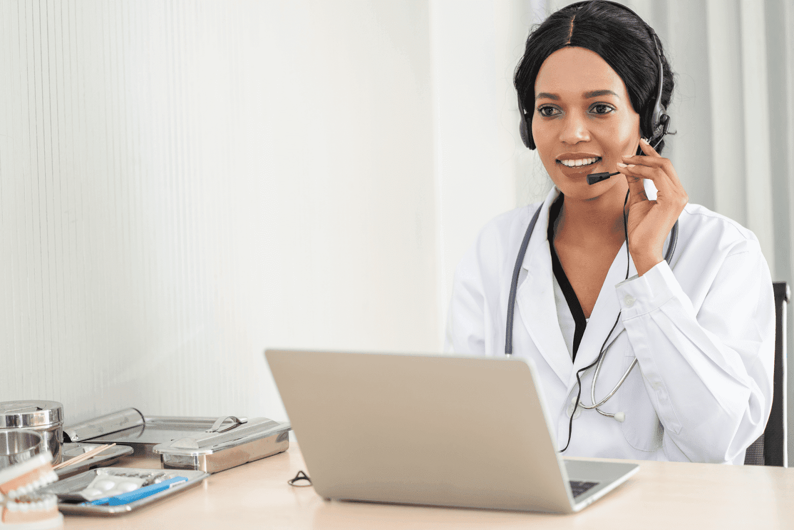 Doctor wearing a headset talking to a patient online using a laptop.