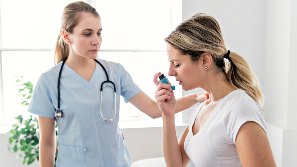 Woman using inhaler in front of medical professional