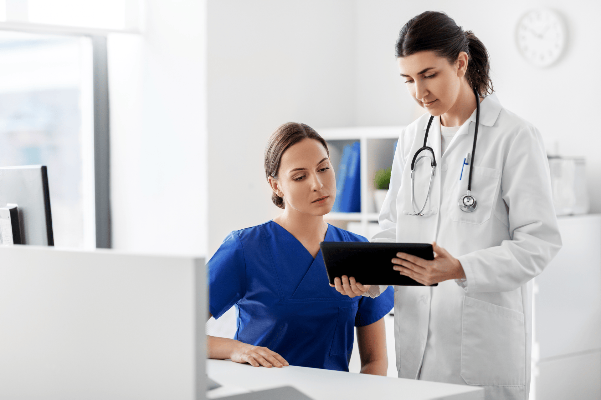 Doctors reviewing patient information on a digital tablet in a medical office.