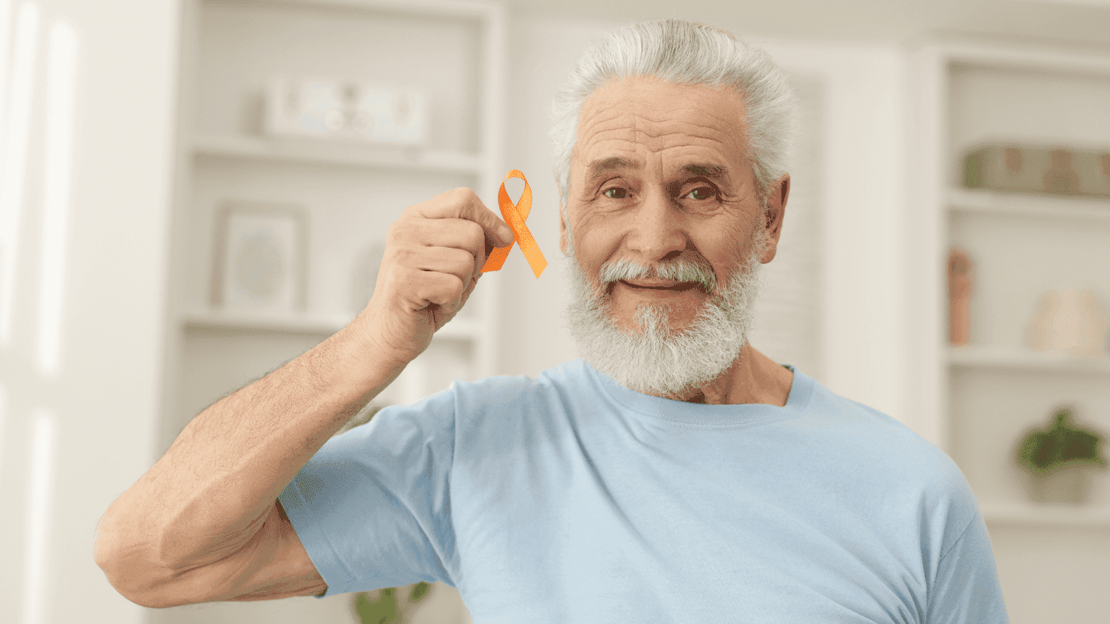 A smiling elderly man in a light blue shirt holds up an orange awareness ribbon, often associated with multiple sclerosis or leukemia