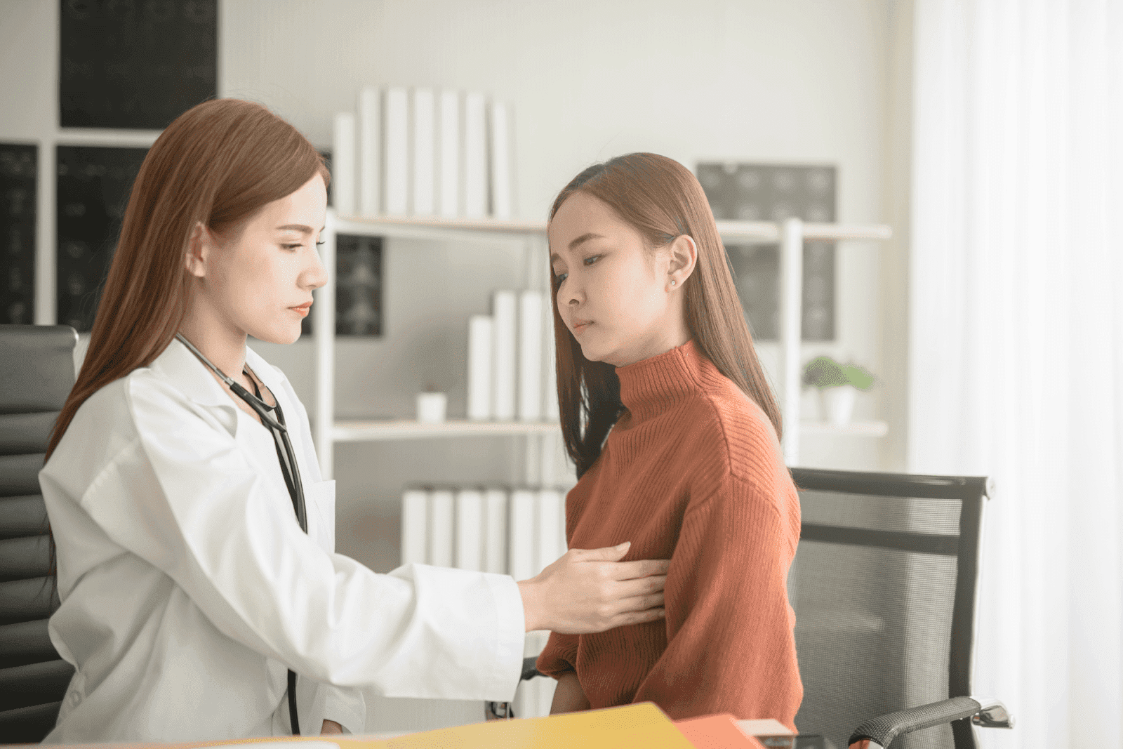 Female doctor performing breast exam on patient in clinic