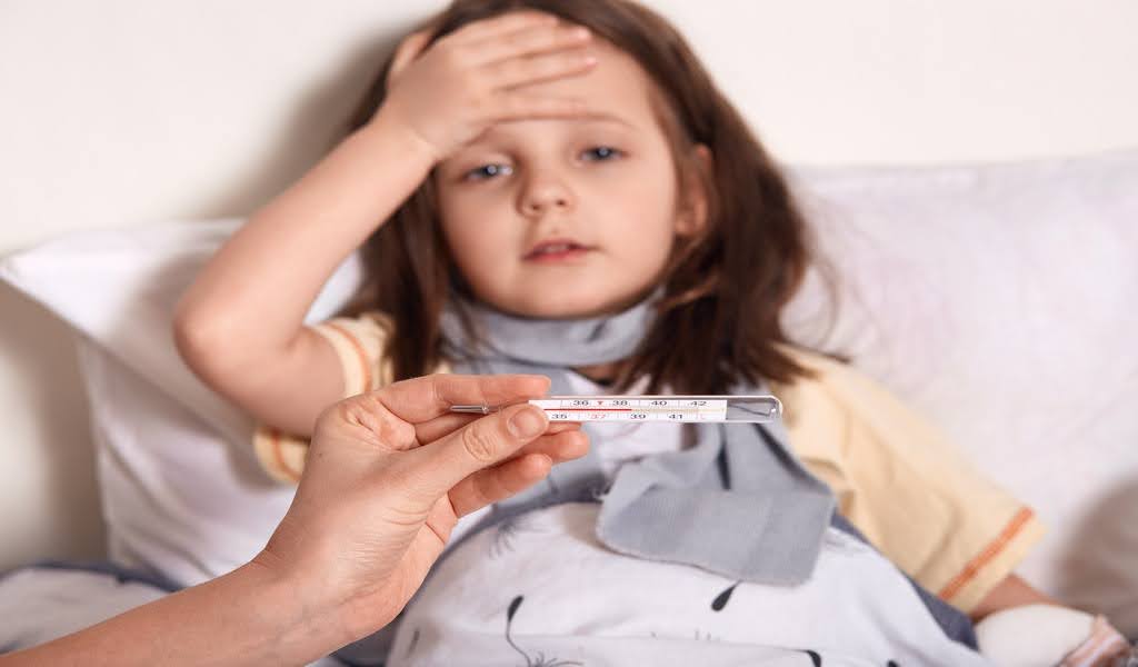 Feverish toddler resting, thermometer in clear focus