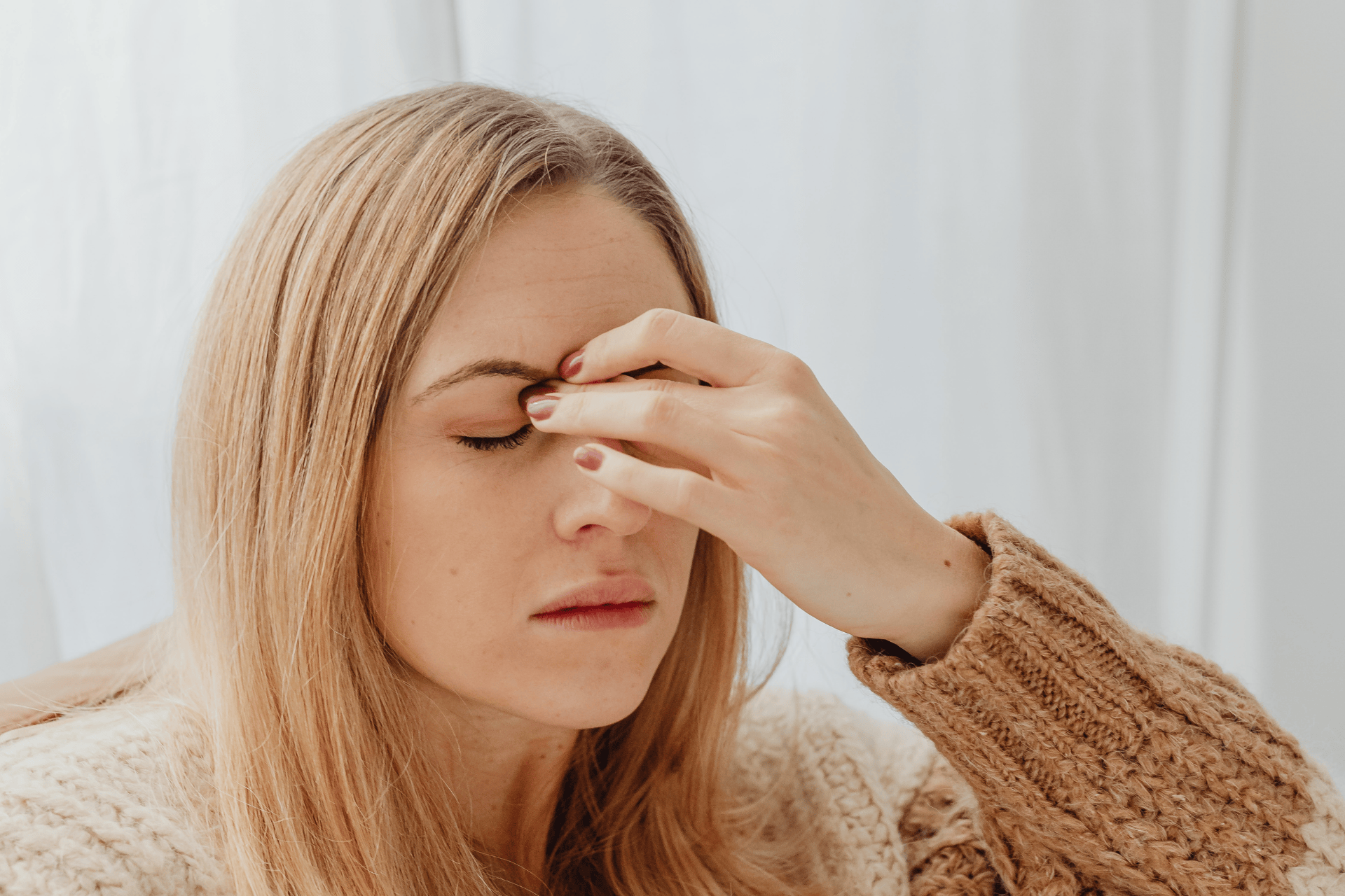 Woman touching her forehead with closed eyes, appearing to have a headache.