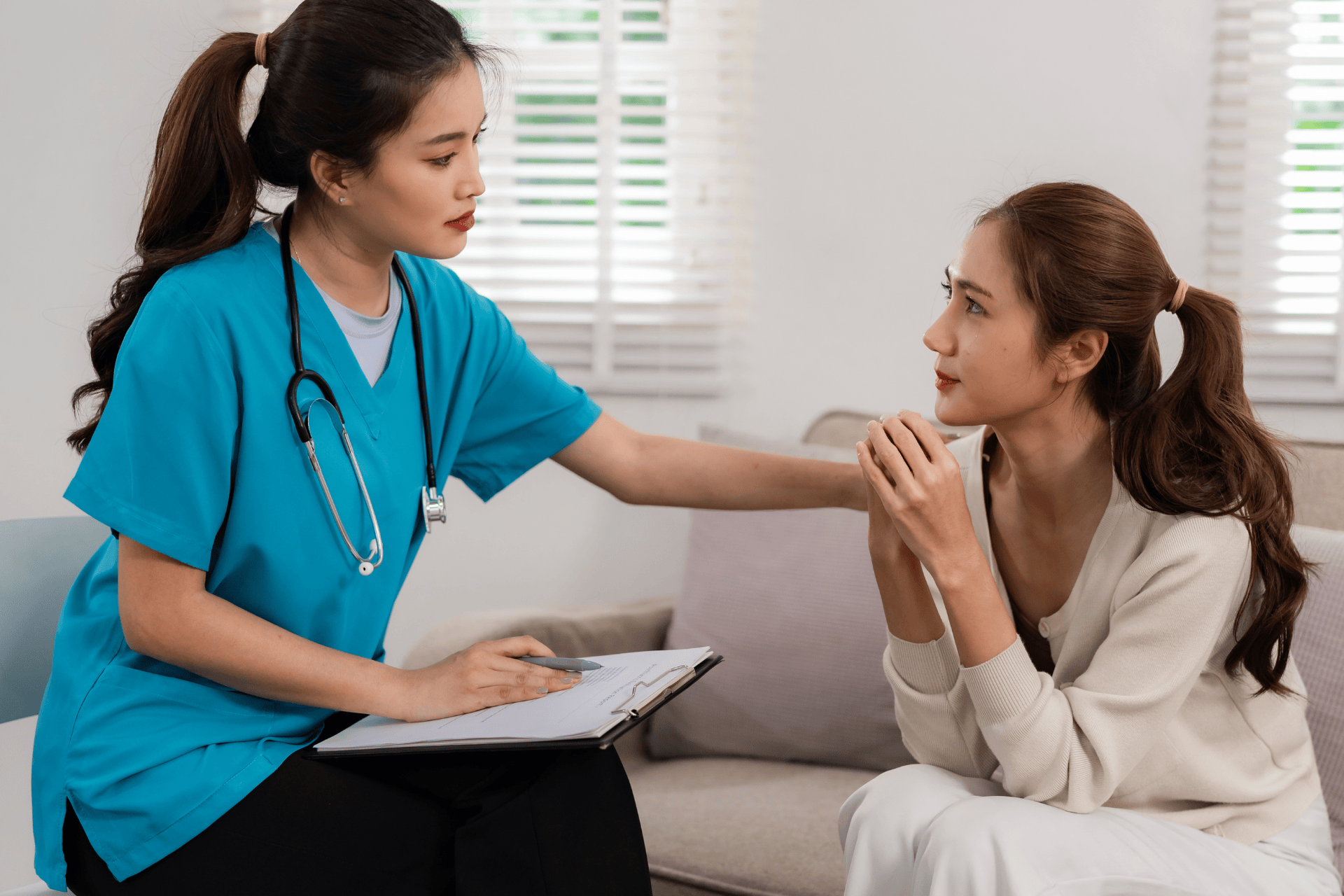 Nurse comforting a patient while discussing medical information at home.
