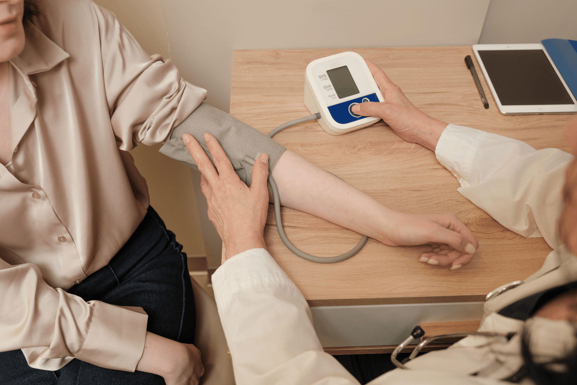 Healthcare professional checking a patient’s blood pressure with a digital monitor.
