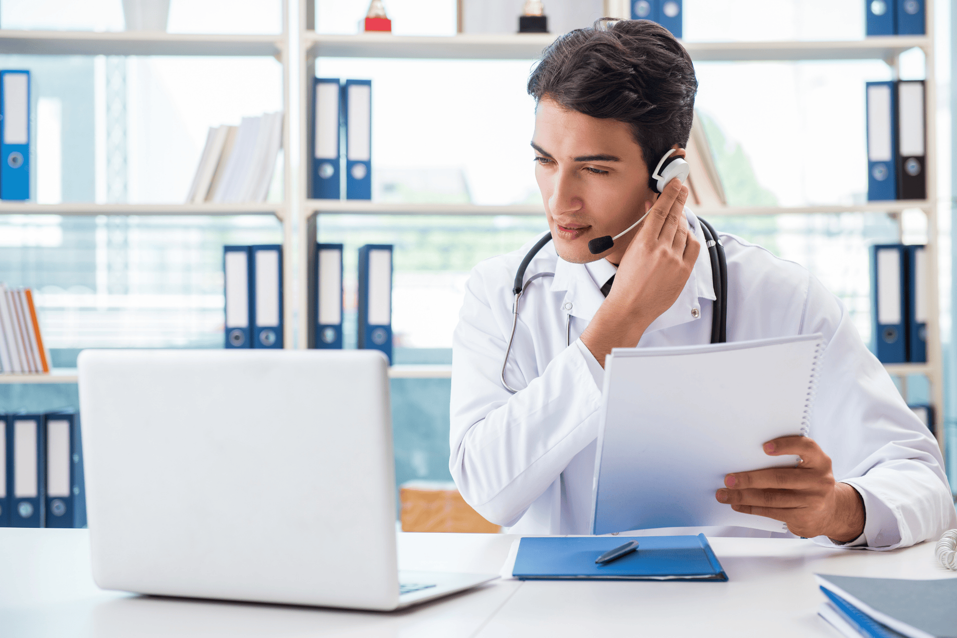 Doctor with a headset holding notes during an online consultation.