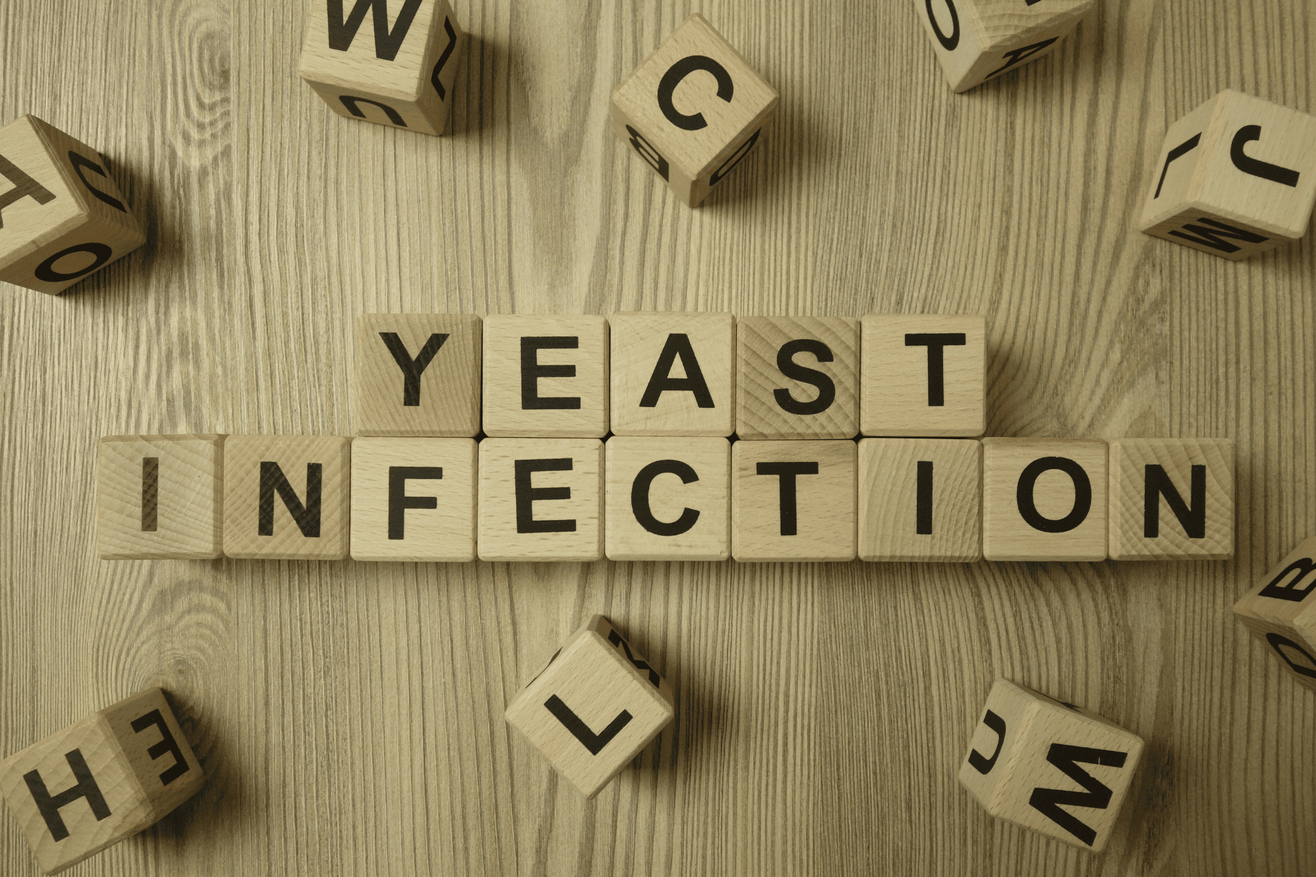 Wooden blocks spelling out the words ‘yeast infection’ on a wooden surface.