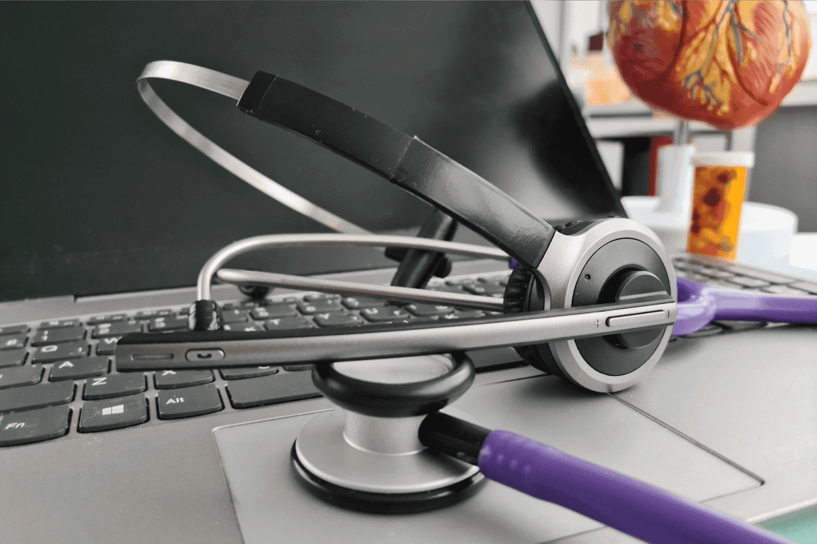 Headset and stethoscope resting on a laptop keyboard.