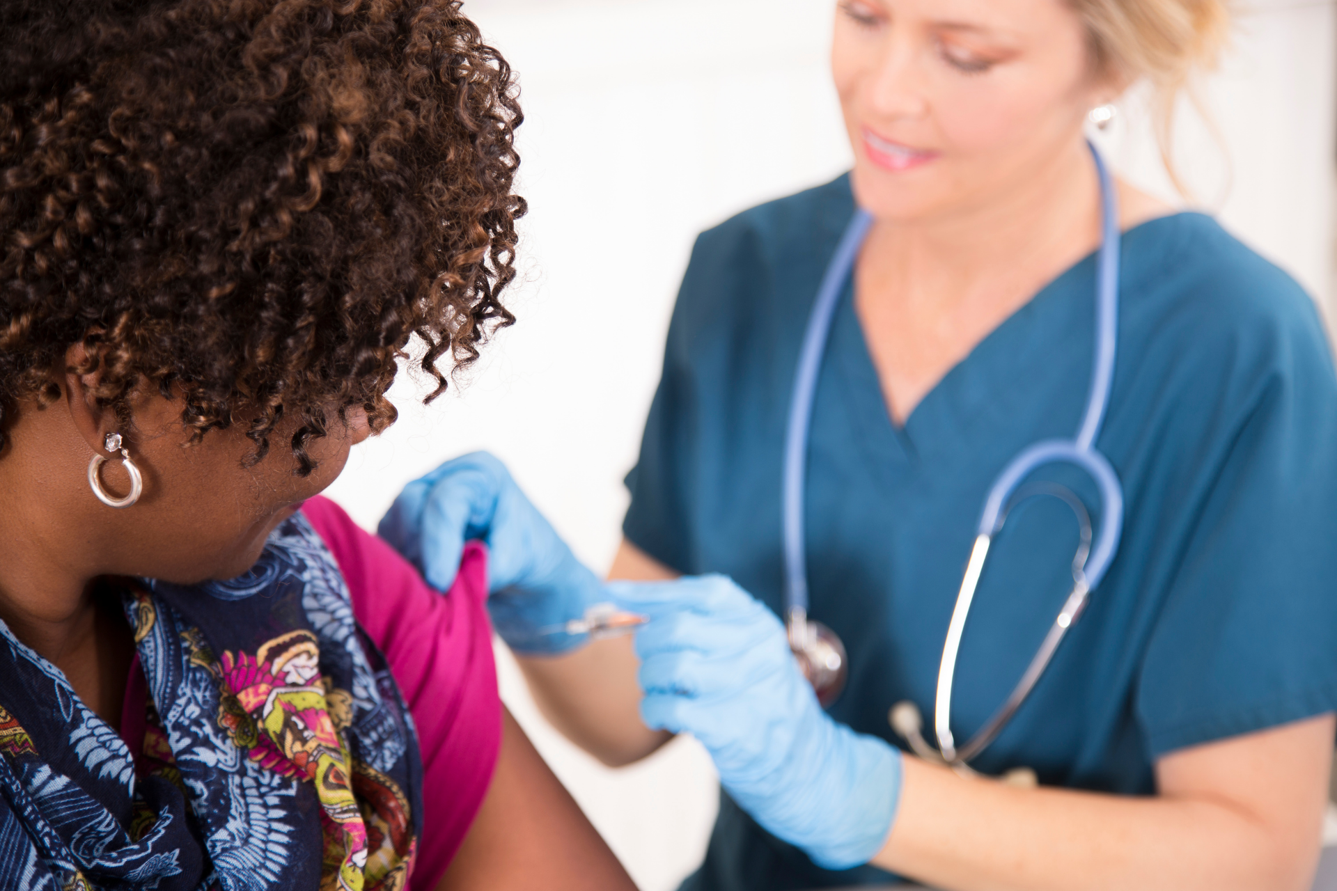 Healthcare professional administering a vaccine injection to an adult woman in a clinical setting