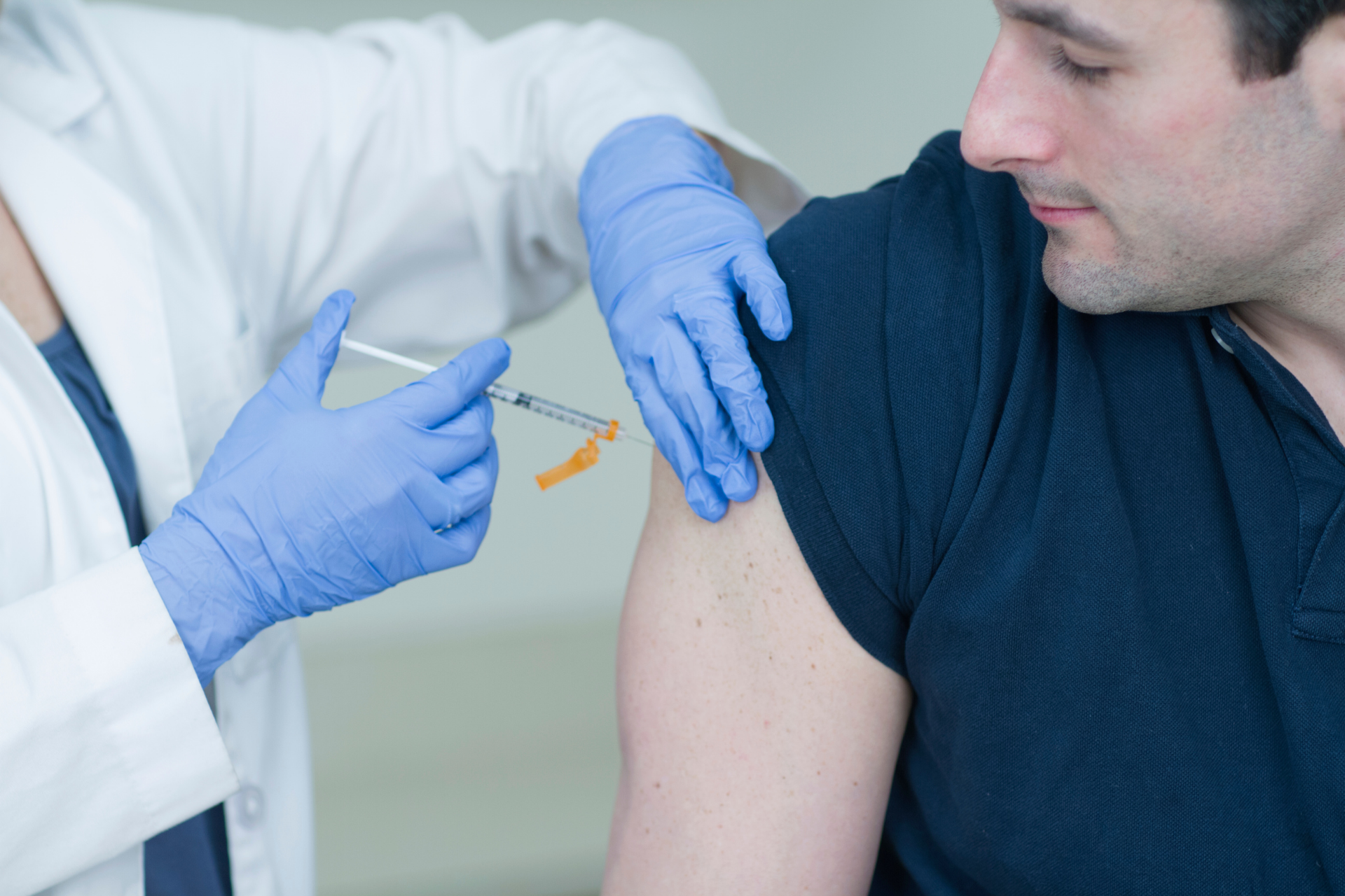 Healthcare professional administering an injection into a man’s upper arm