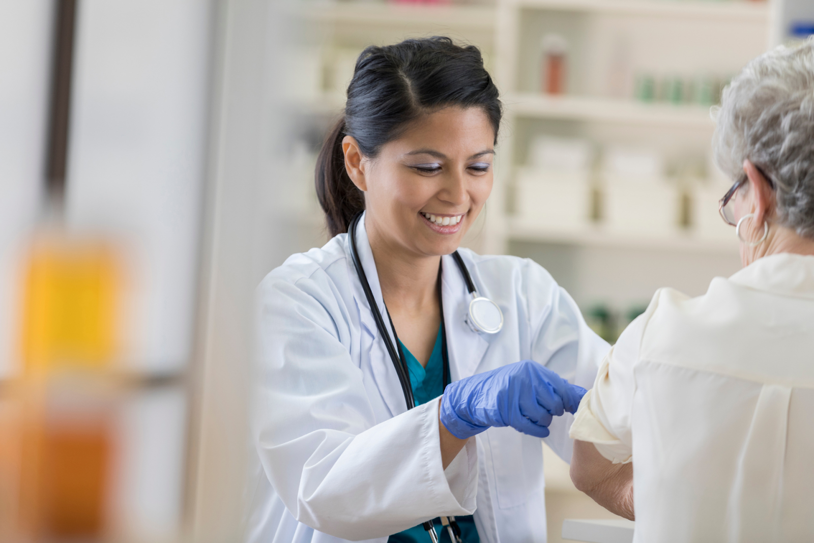 Healthcare provider administering a vaccine to an older adult’s arm in a clinical setting.