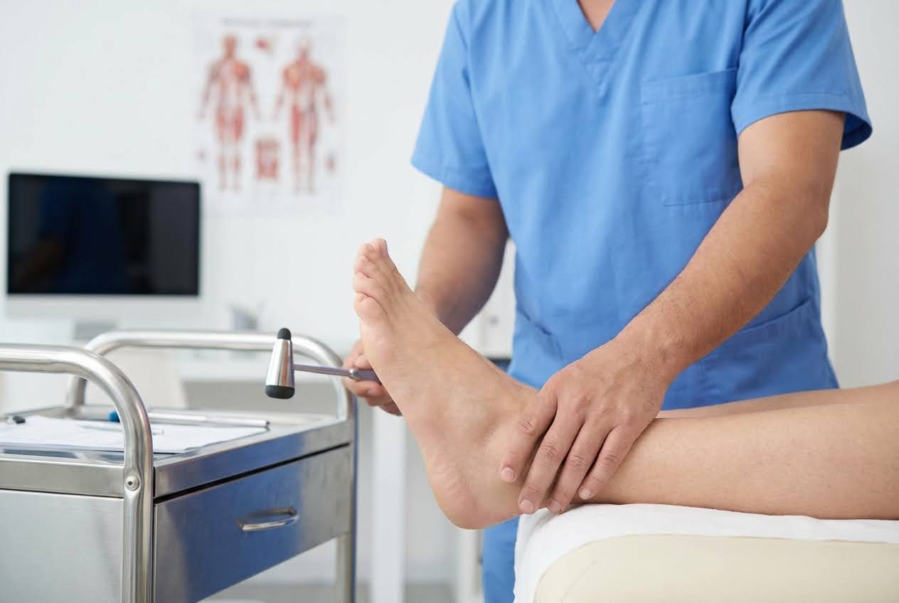 Healthcare provider testing a patient’s ankle reflex with a reflex hammer during a neurological exam