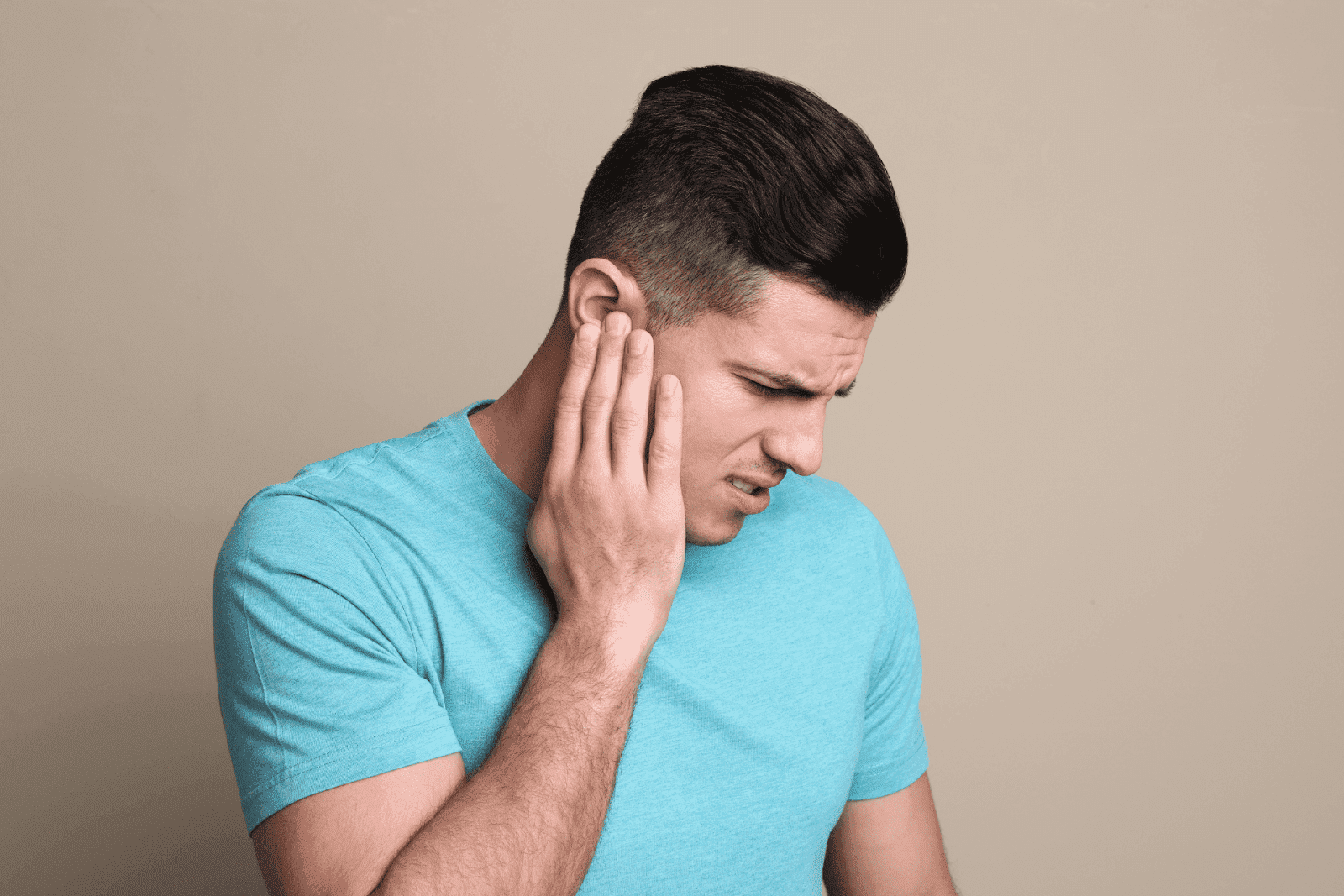 Man holding ear in discomfort.