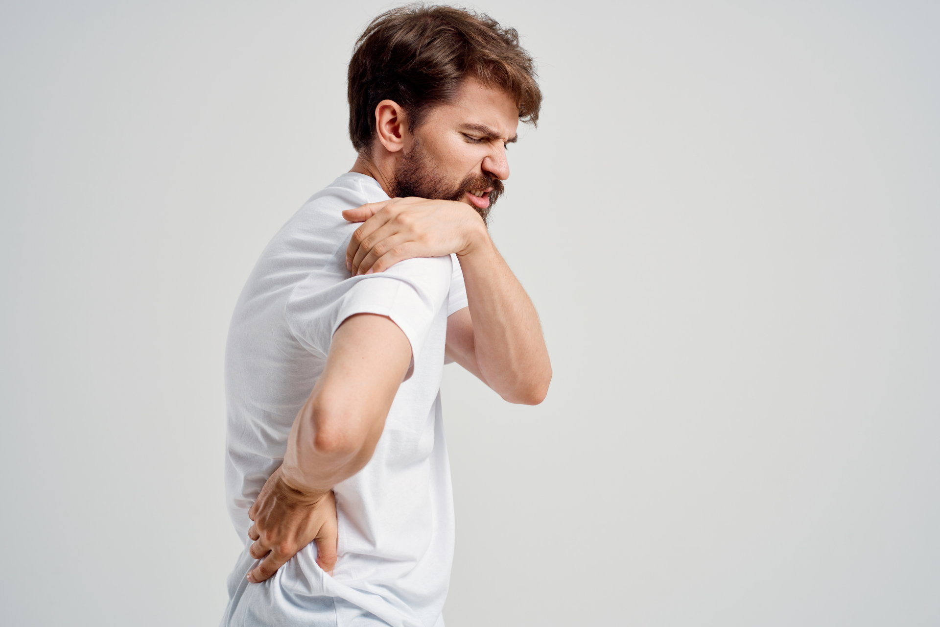 Man holding his shoulder and lower back in pain
