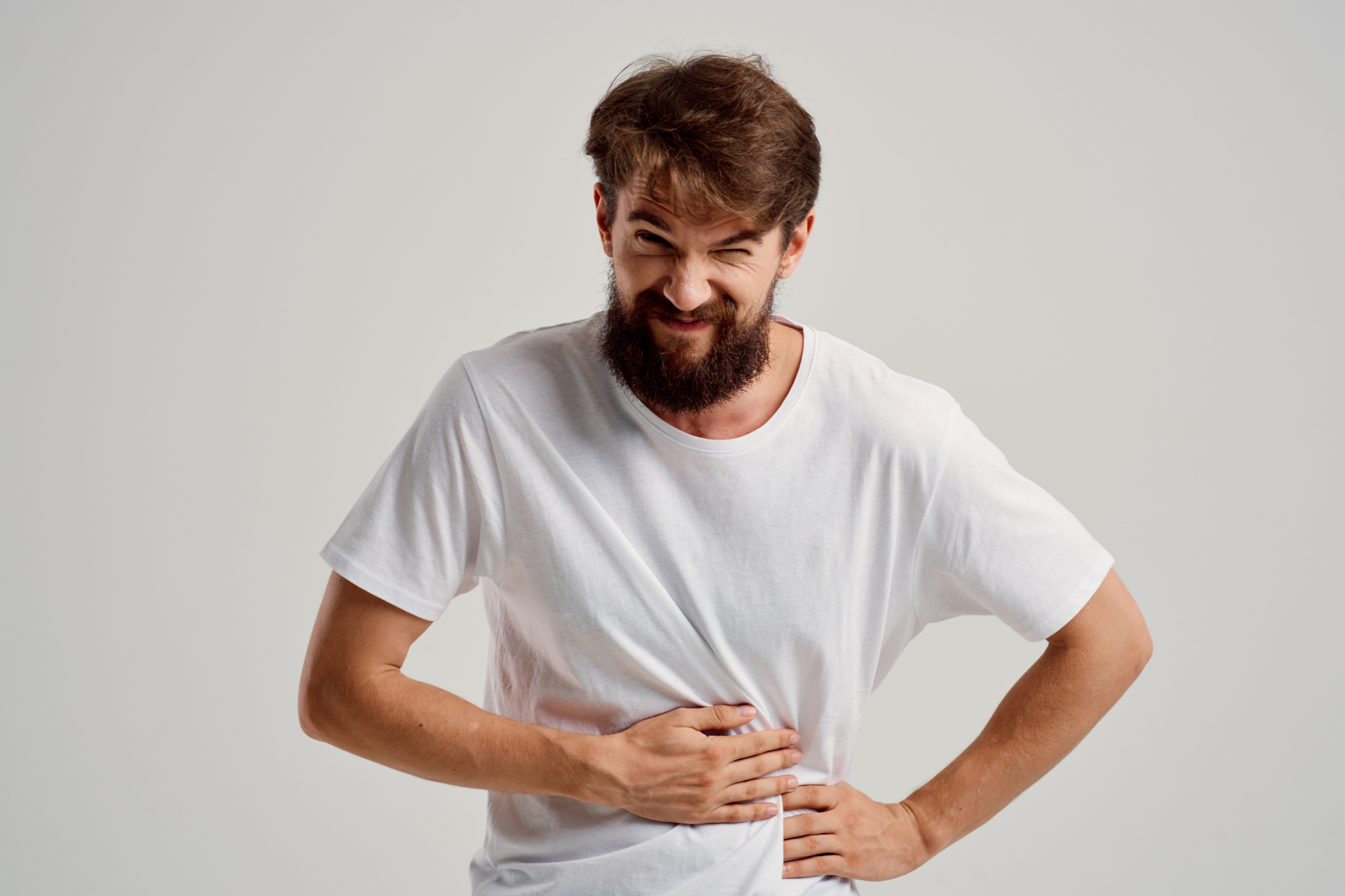 Man holding his stomach with a pained expression, indicating abdominal discomfort