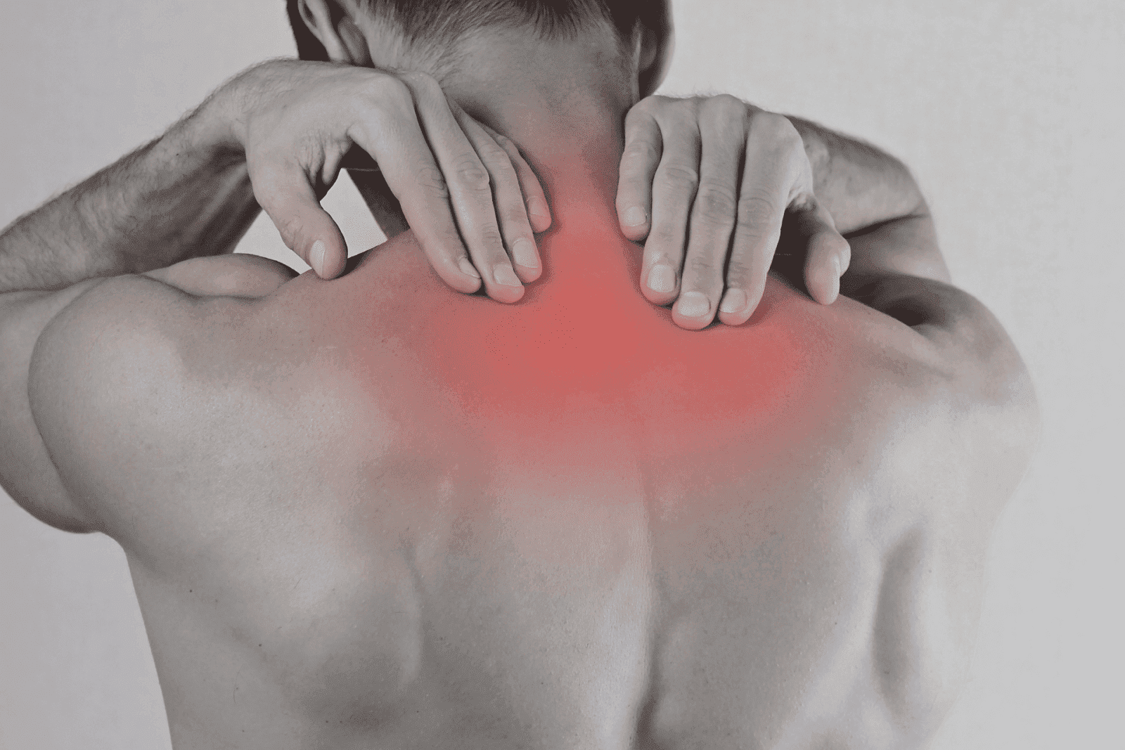 Man holding his upper back in pain with a red highlighted area, indicating pain