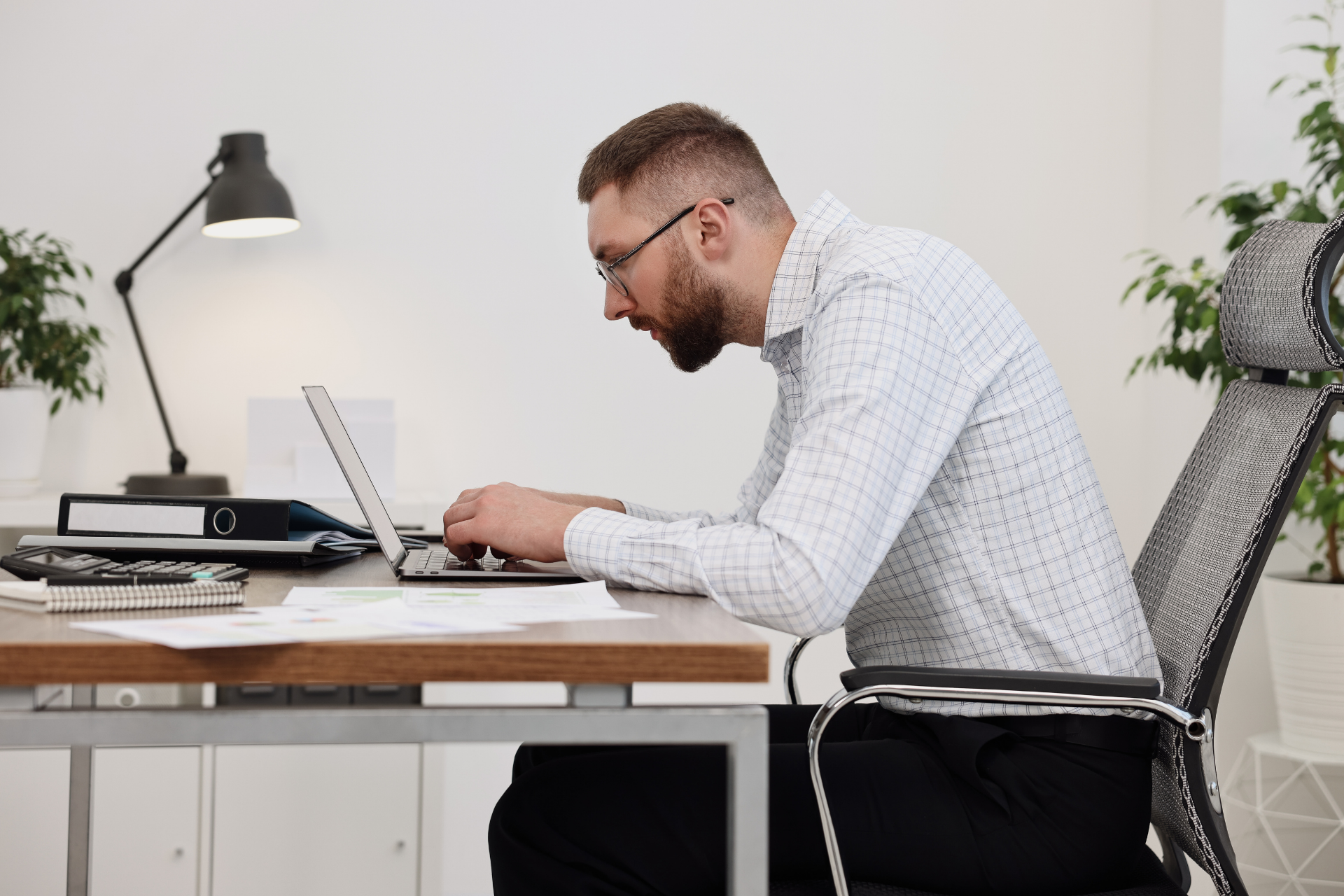Man sitting hunched over a laptop at a desk