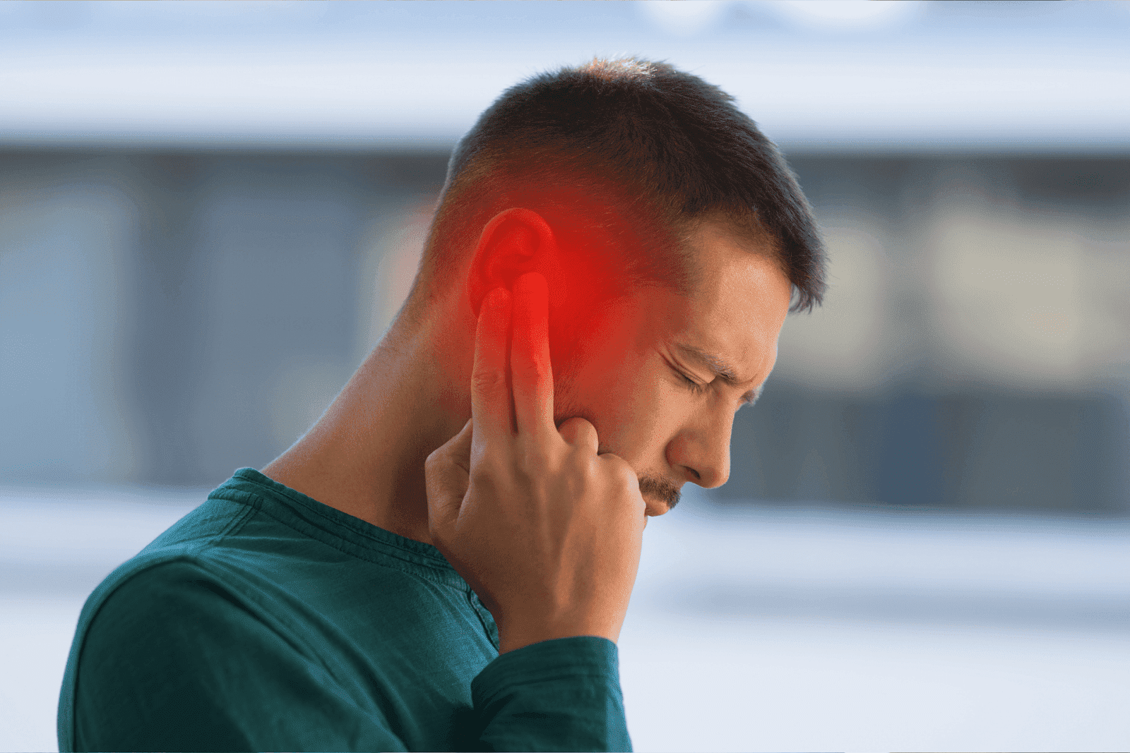 Man touching his ear with a pained expression, highlighted red area indicating ear pain or infection