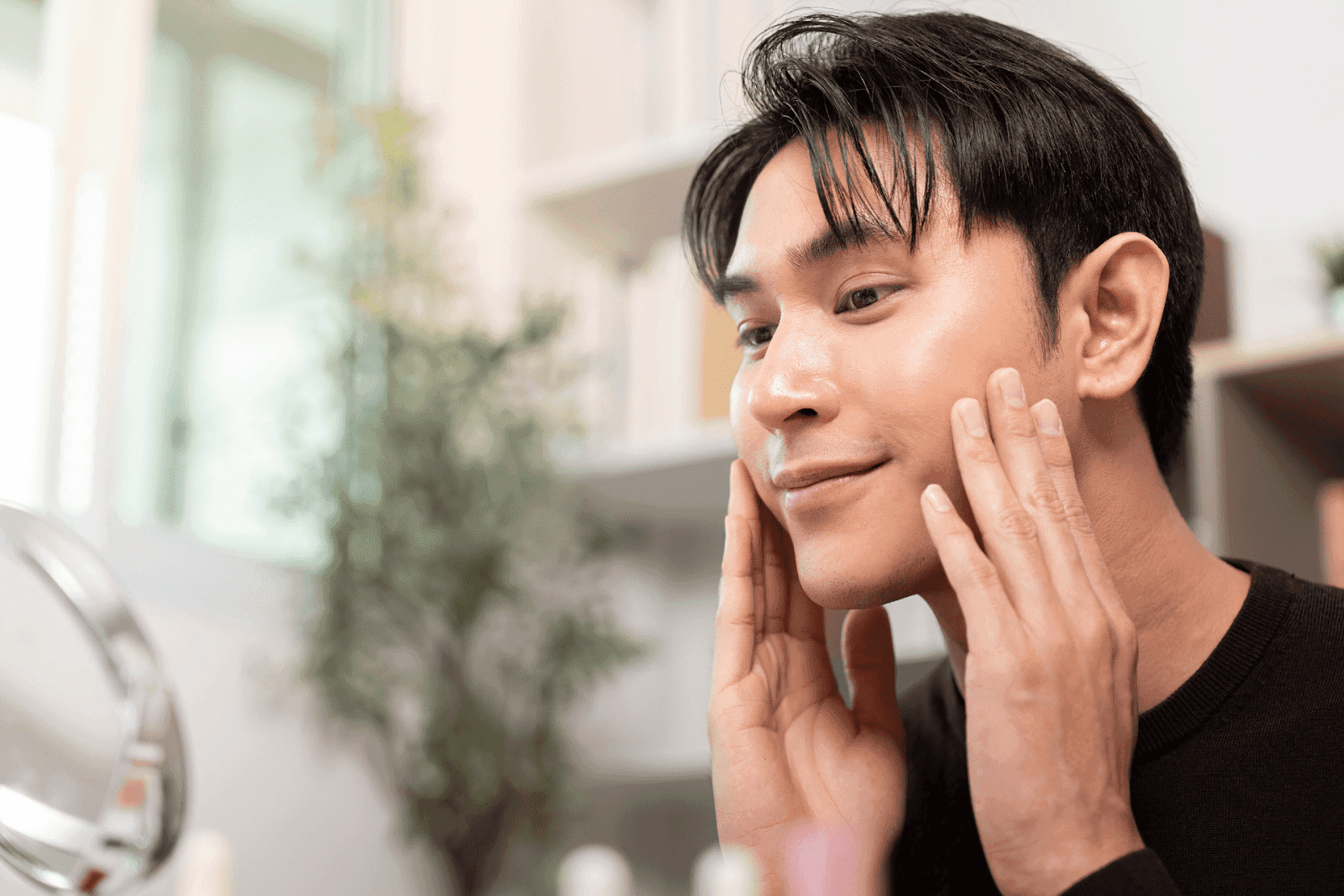 Man touching his face and smiling while looking in a mirror.