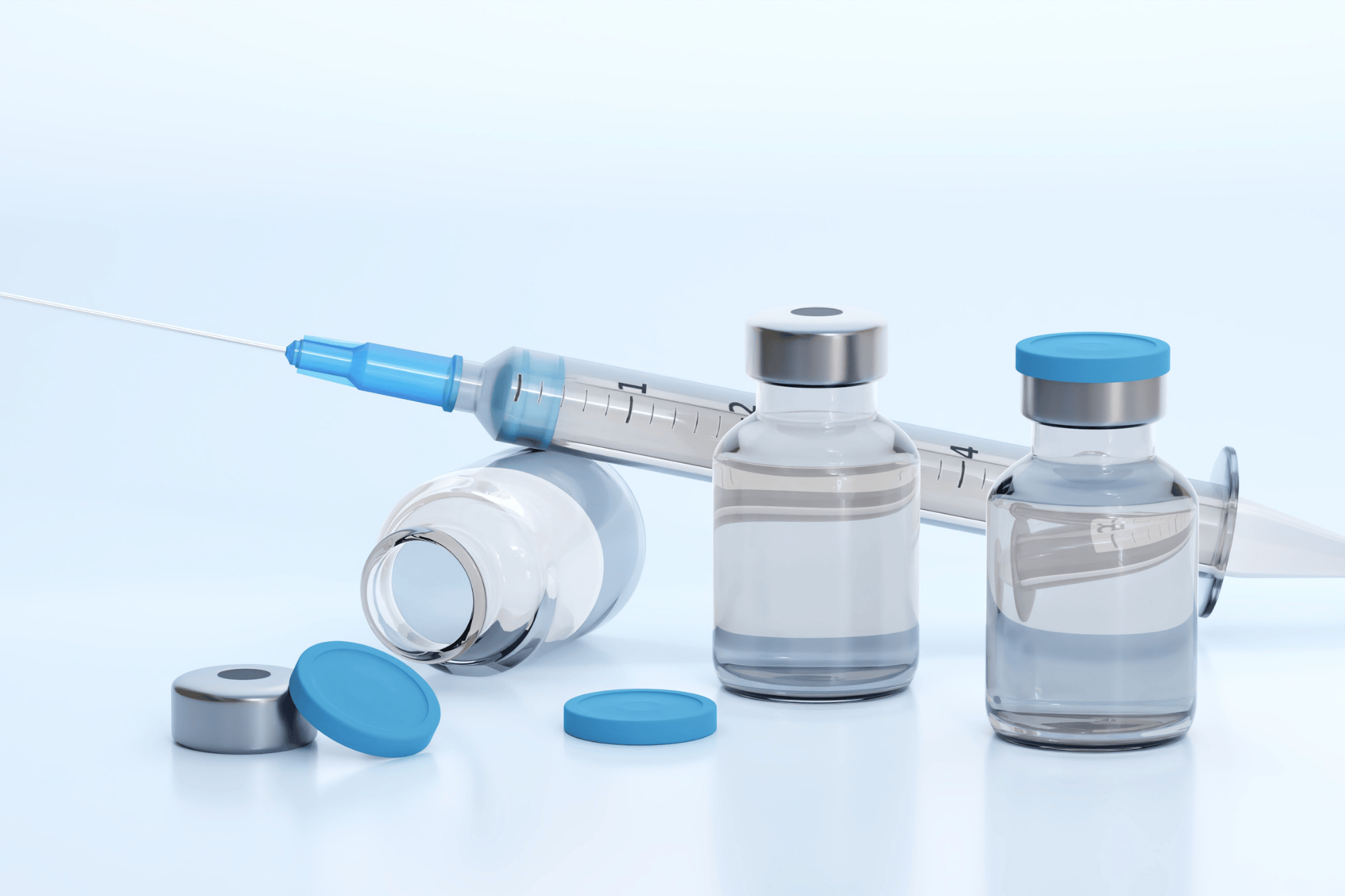 Medical vials and a syringe on a clean surface.