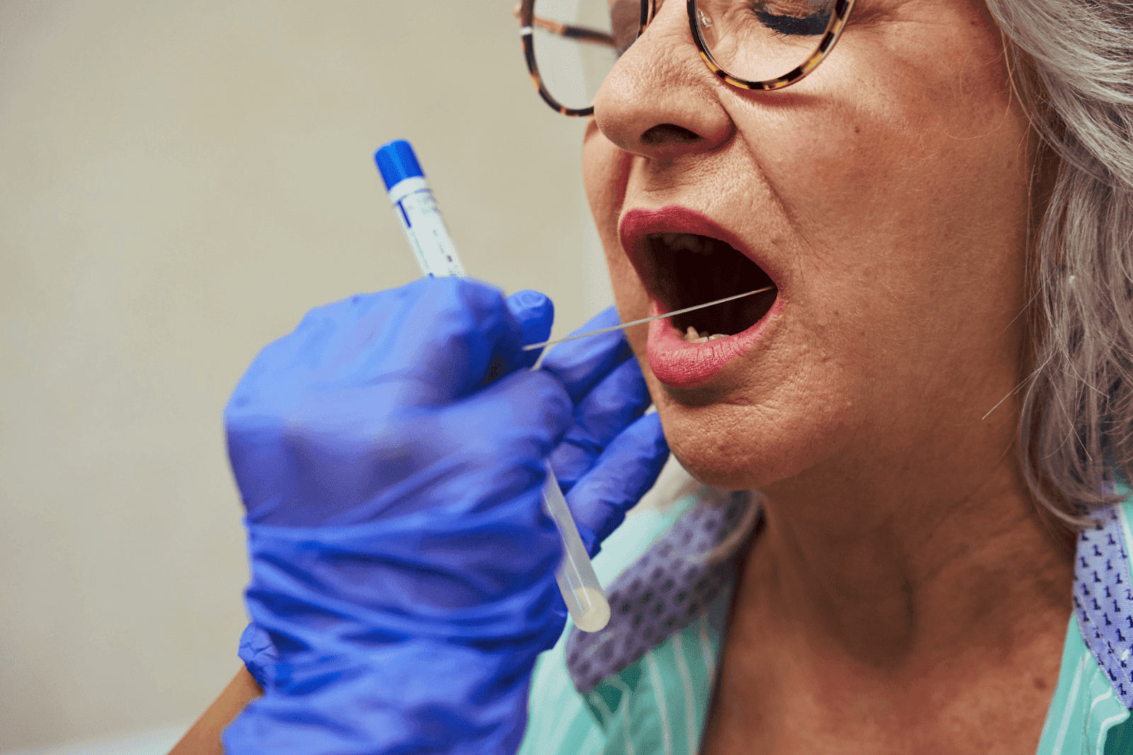 Older woman having a mouth swab test by a healthcare provider
