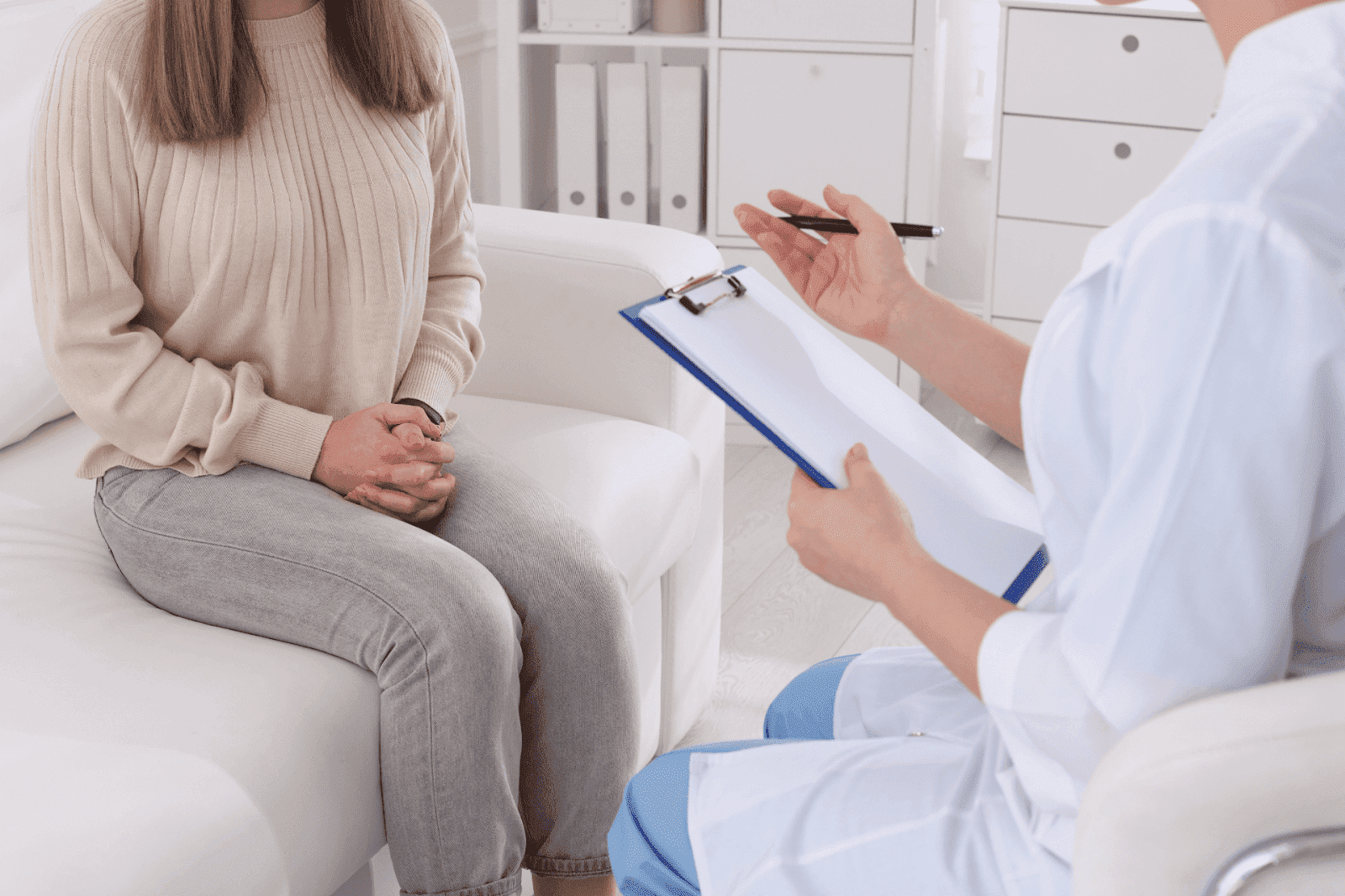 Patient consulting doctor with clipboard in office.