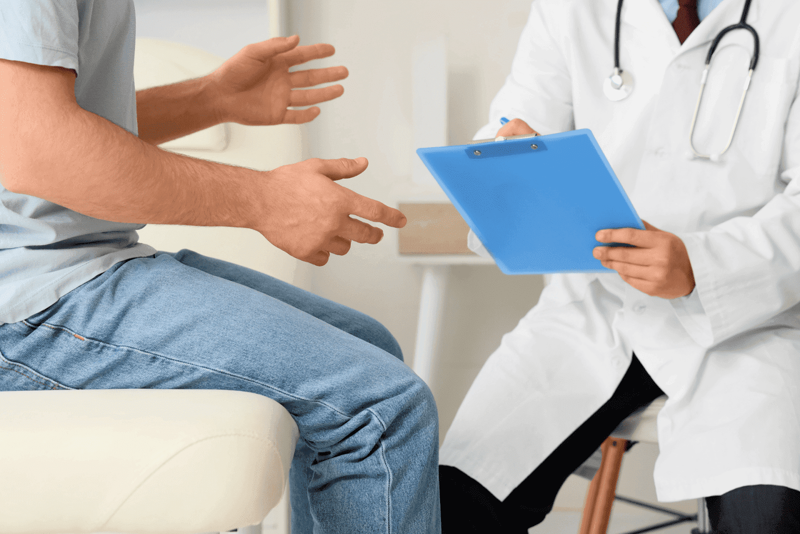 Patient consulting with a doctor holding a blue clipboard in a medical office.